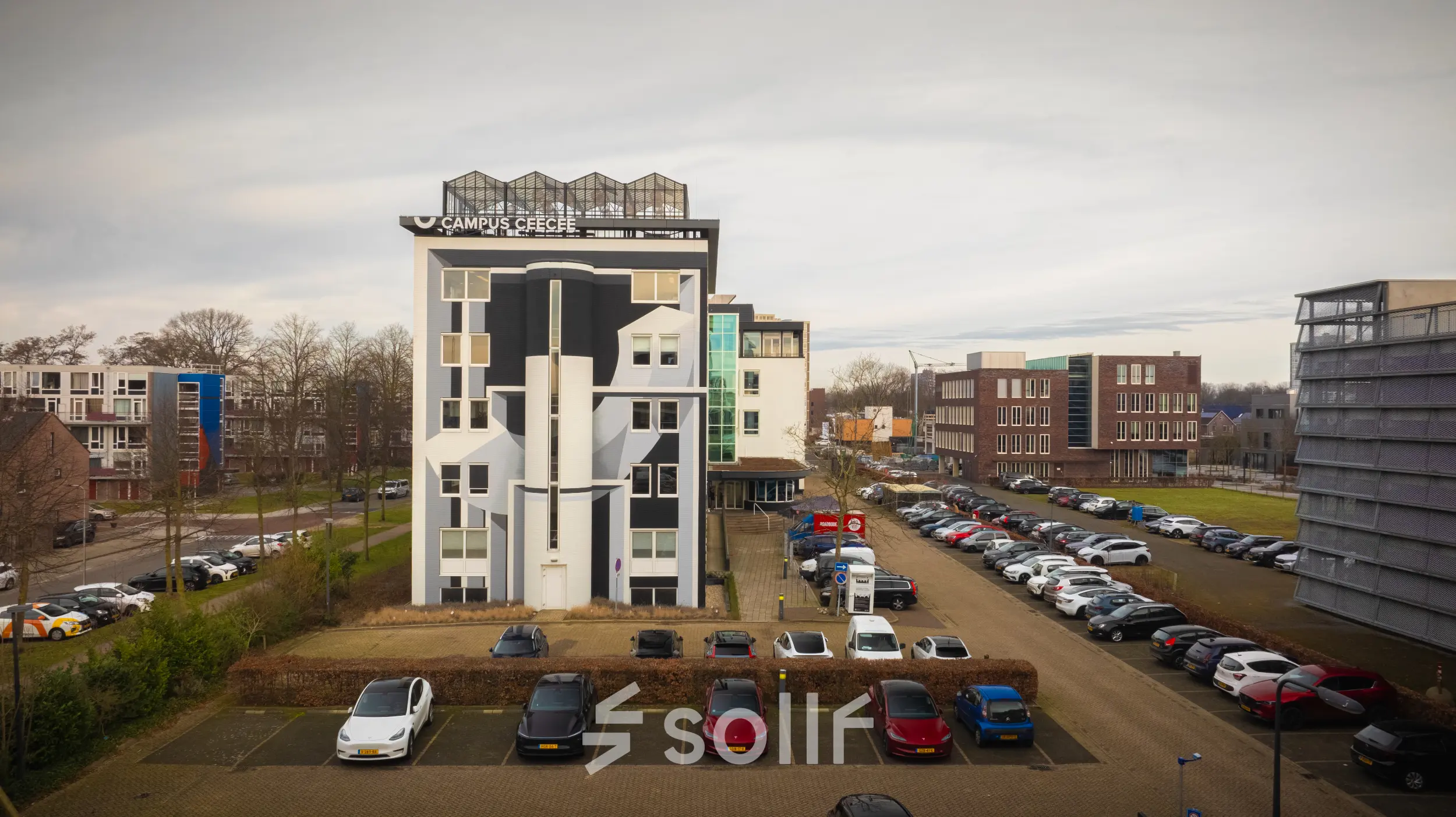 Exterior view of the office building at Brouwerijstraat 1 in Enschede with adjacent parking area, suitable for office space rental.
