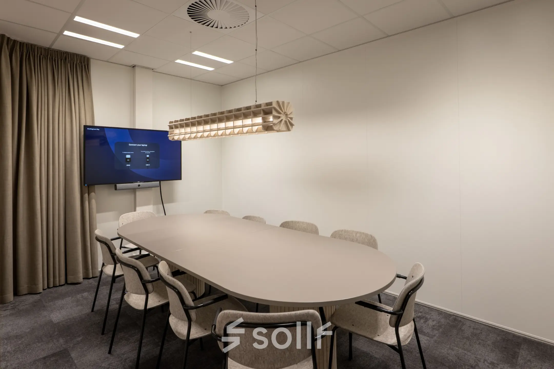 Modern conference room at Kuipersdijk 2-4, Enschede, available for office space rental, featuring a sleek table and chairs with a screen for presentations.