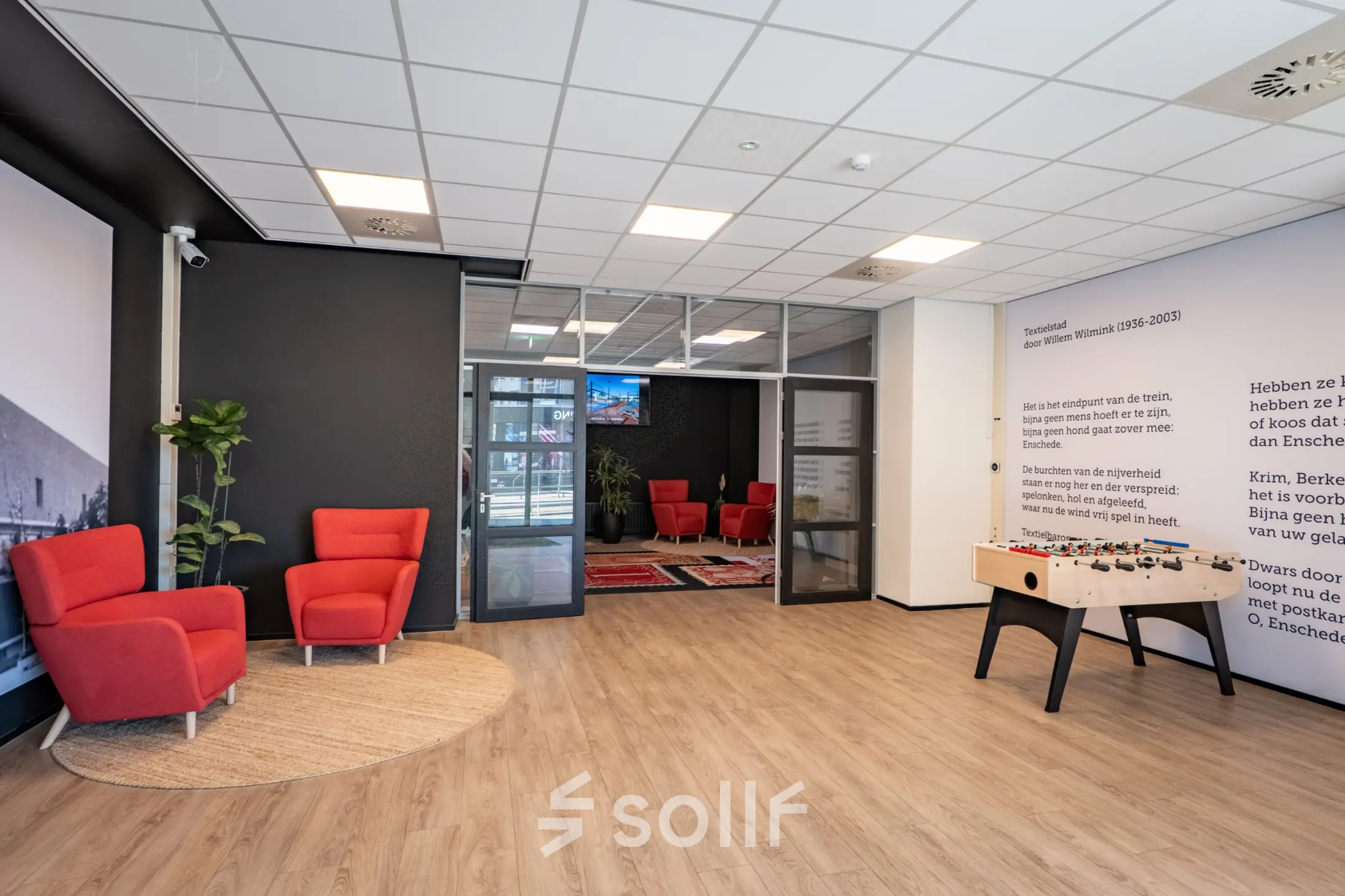 Bright office space at Kuipersdijk 2-4, Enschede with modern decor, featuring red chairs and a foosball table available for rent.