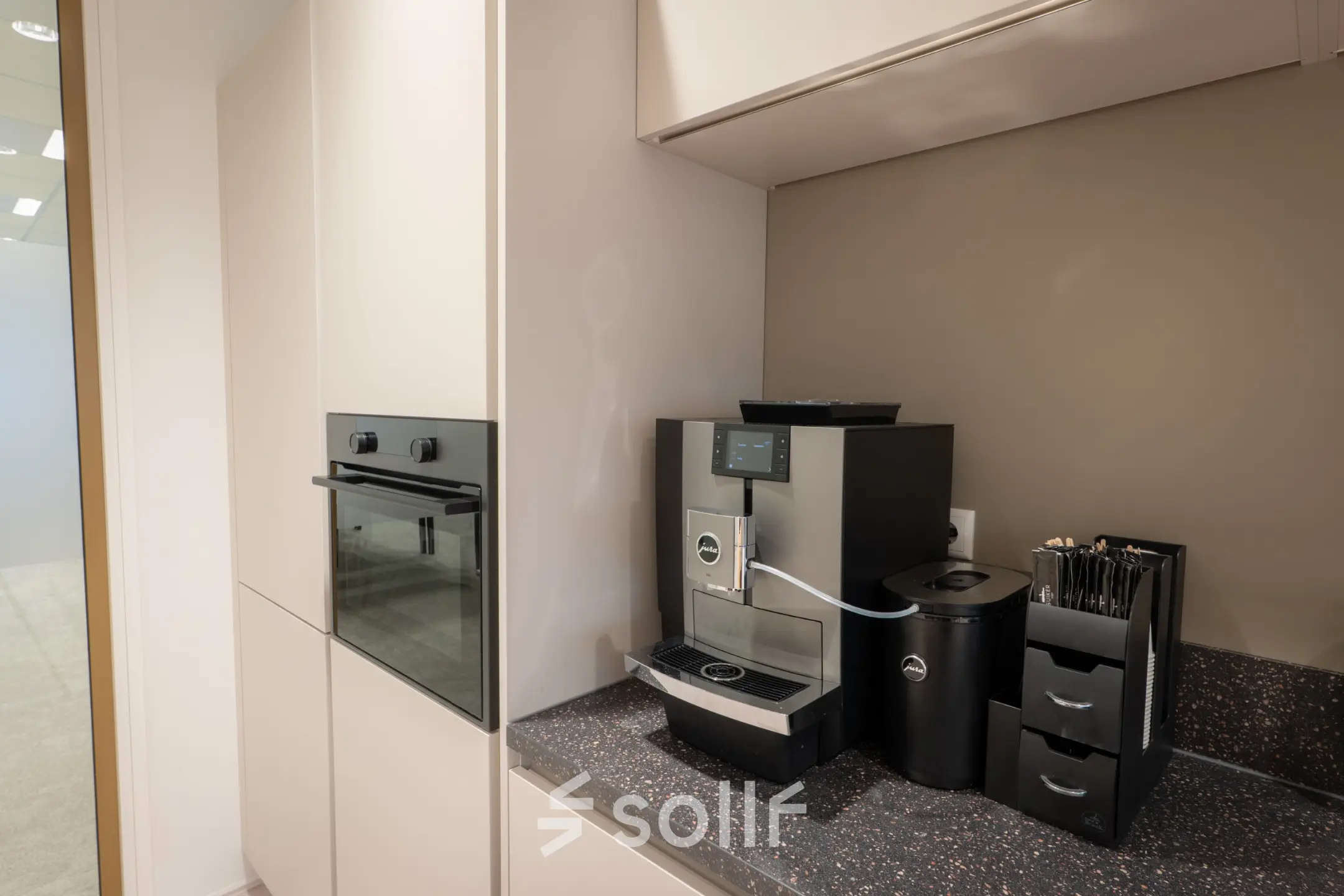 Modern kitchenette area with a coffee machine and cabinetry, part of an office space rental in Kuipersdijk 2-4, Enschede.