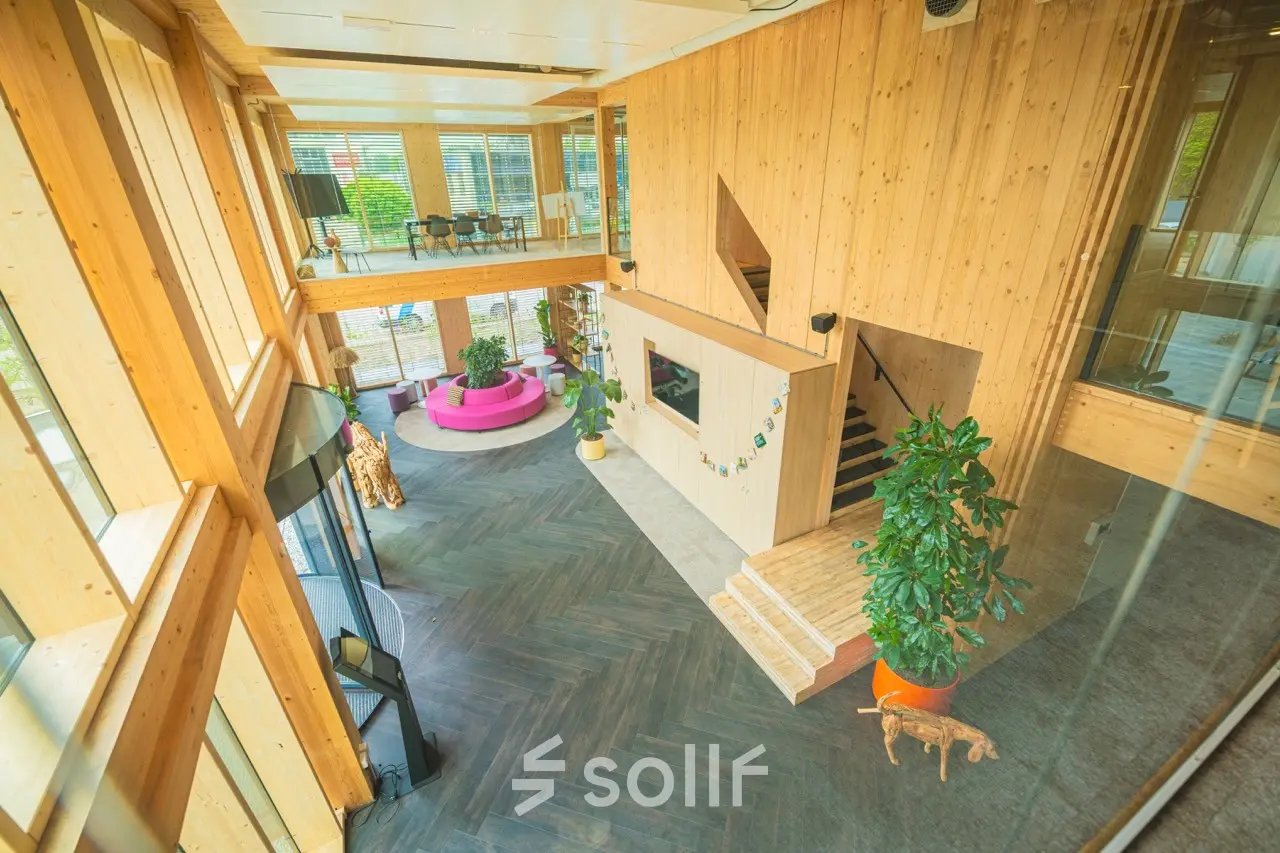 Wooden-interior office space on Moutlaan 1-23 in Enschede, showcasing a spacious, modern design with a mezzanine and large plants, ideal for office space rental.