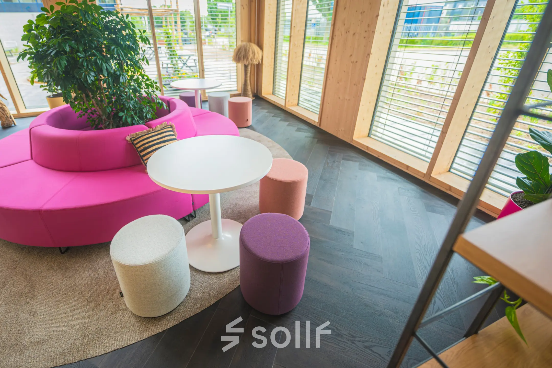 Bright office space at Moutlaan 1-23, Enschede featuring colorful seating, round tables, and large windows, perfect for rent office space with a modern touch.