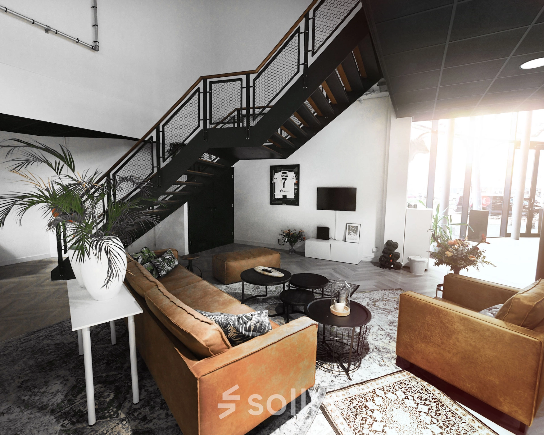 Modern furnished office space available for rent at Parkweg 102, Enschede featuring a stylish seating area with sofas under a staircase and a TV. Ideal for office space rental.