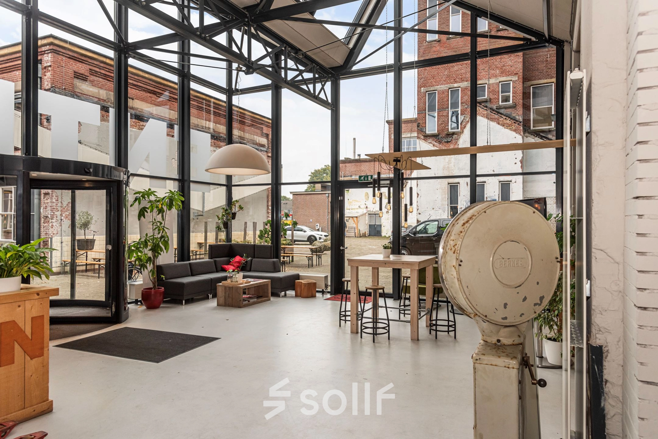 Spacious office space at Rigtersbleek-Zandvoort 10, Enschede, featuring large windows, a seating area, and high ceilings. Ideal for office space rental.