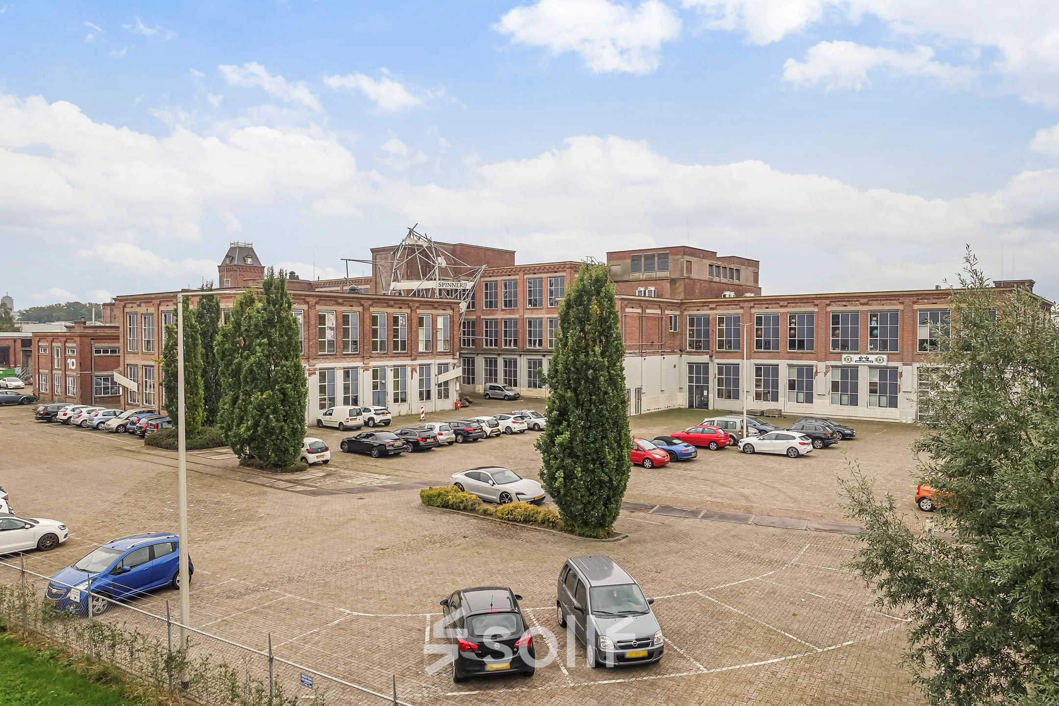 Exterior view of office spaces for rent at Rigtersbleek-Zandvoort 10, Enschede, featuring a spacious parking area with cars.