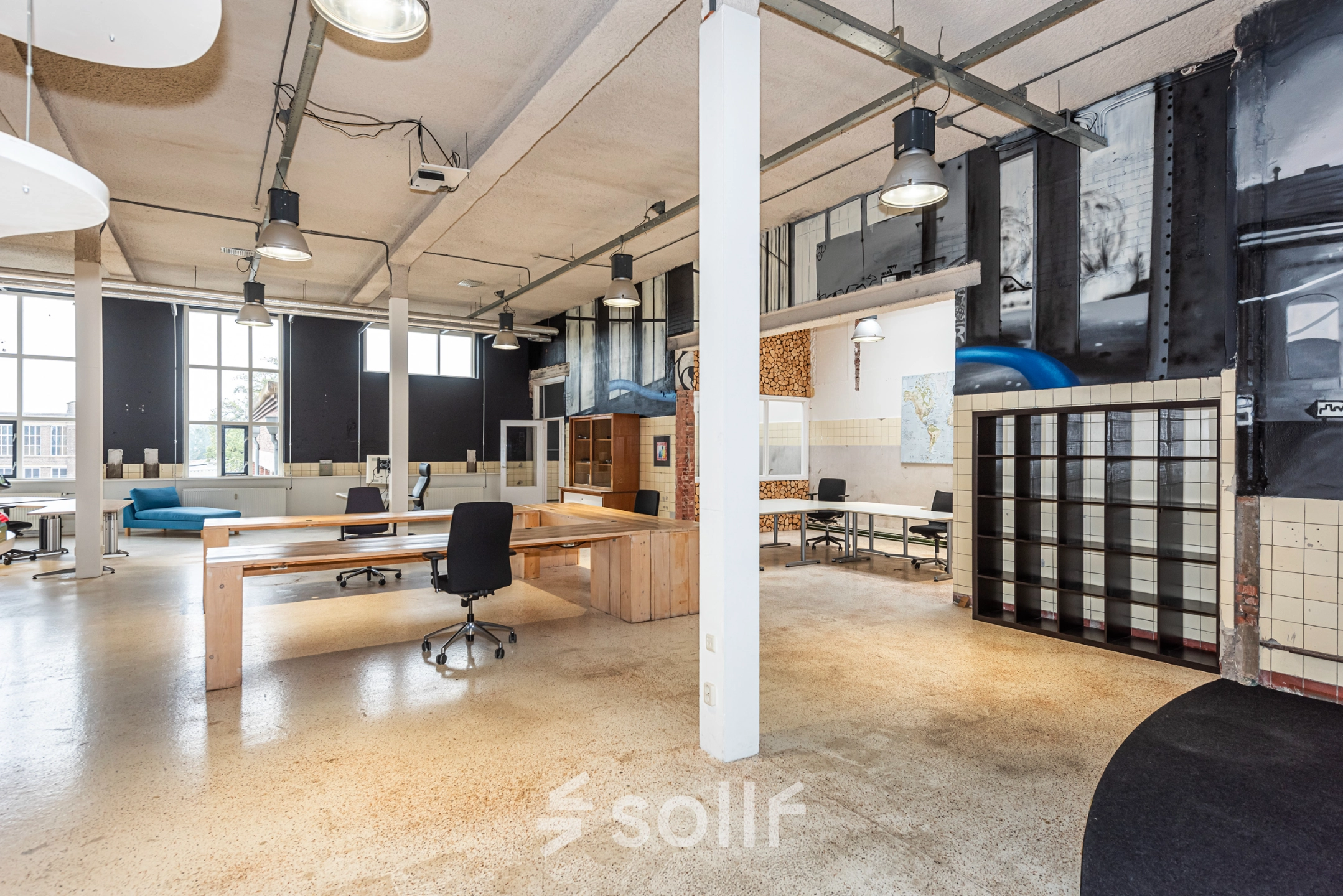 Modern office space rental at Rigtersbleek-Zandvoort 10, Enschede, featuring an open floor plan with desks and chairs, industrial lighting, and large windows.