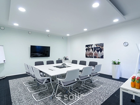 Modern office conference room at Mergenthaler Allee 15-21, Eschborn available for office space rental. Features a sleek table, comfortable chairs, and wall decor.