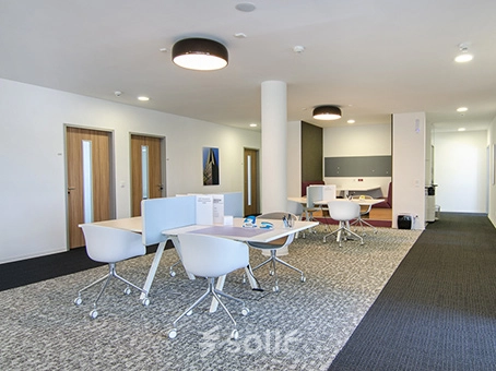 Modern furnished office space at Mergenthaler Allee 15-21 in Eschborn, featuring sleek desks with chairs and a comfortable seating area, ideal for office space rental.