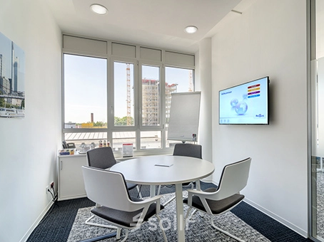 Bright office space with a round table and chairs, located at Mergenthaler Allee 15-21 in Eschborn, ideal for office space rental with large windows offering city views.