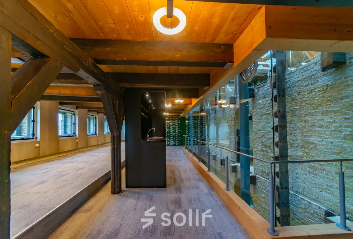 Interior view of an office space available for rent at Prins Hendrikkade 3, Franeker, showcasing a modern design with exposed beams and ample natural light.