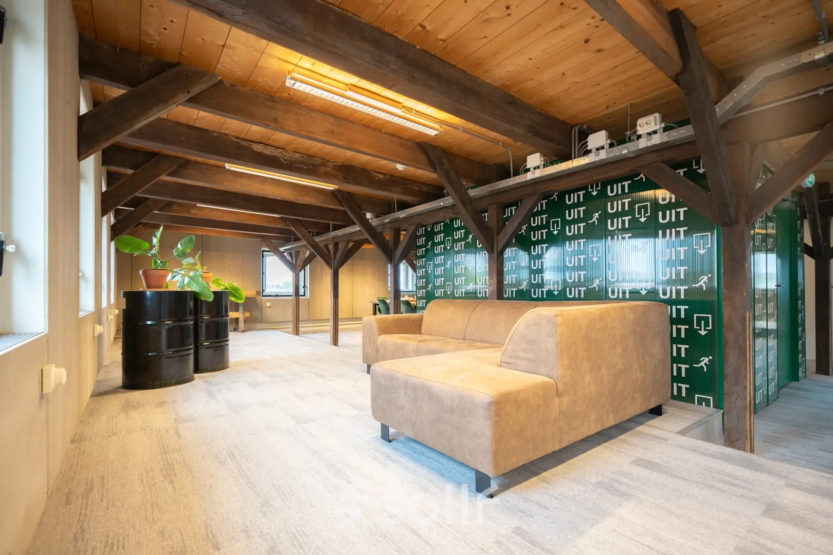 A cozy office space with wooden beams, a sofa, and a plant, available for rent at Prins Hendrikkade 3, Franeker.