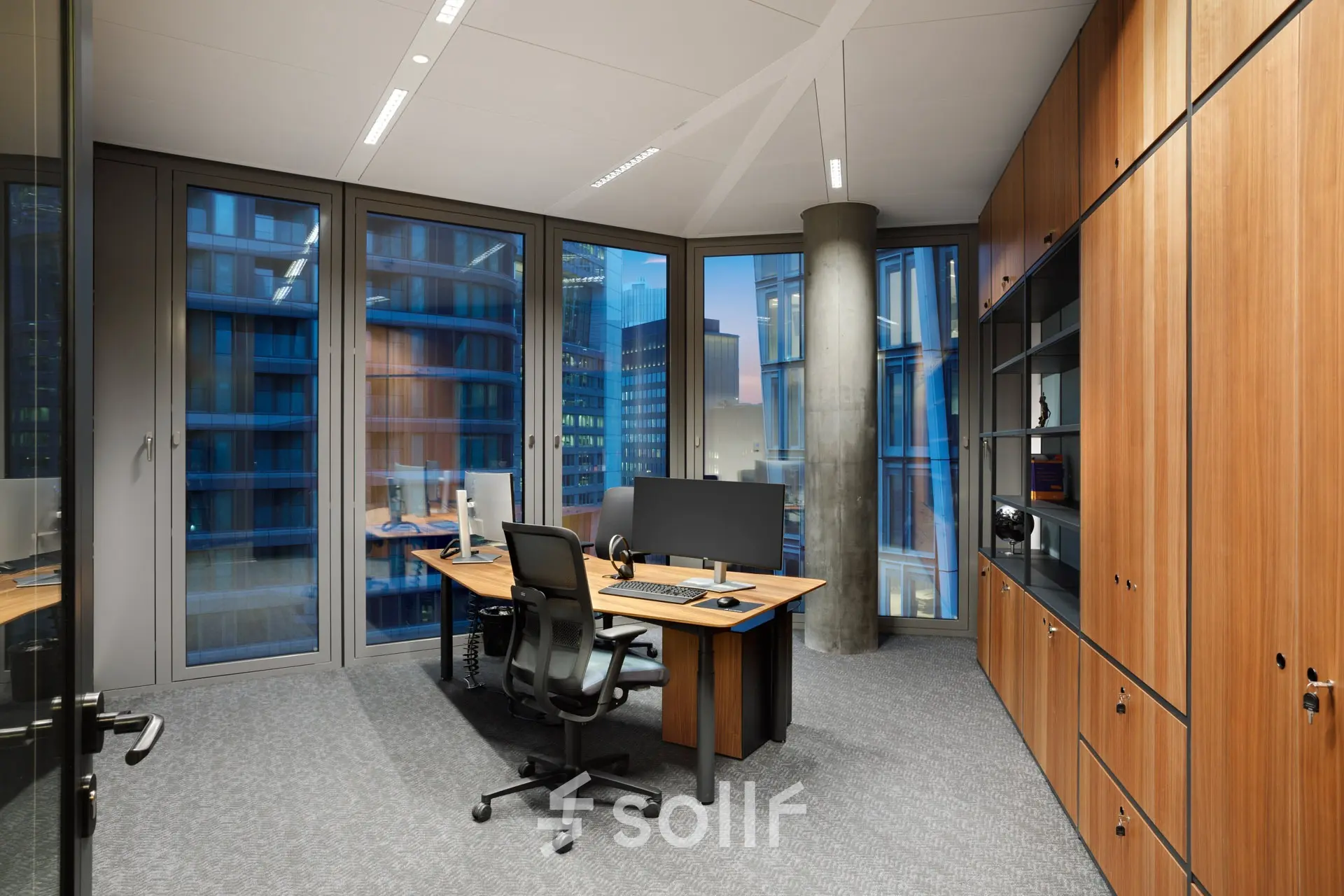 Modern office space with large windows, a wooden desk, ergonomic chair, and storage cabinets at Junghofstraße 9, Frankfurt Center; ideal for office space rental.