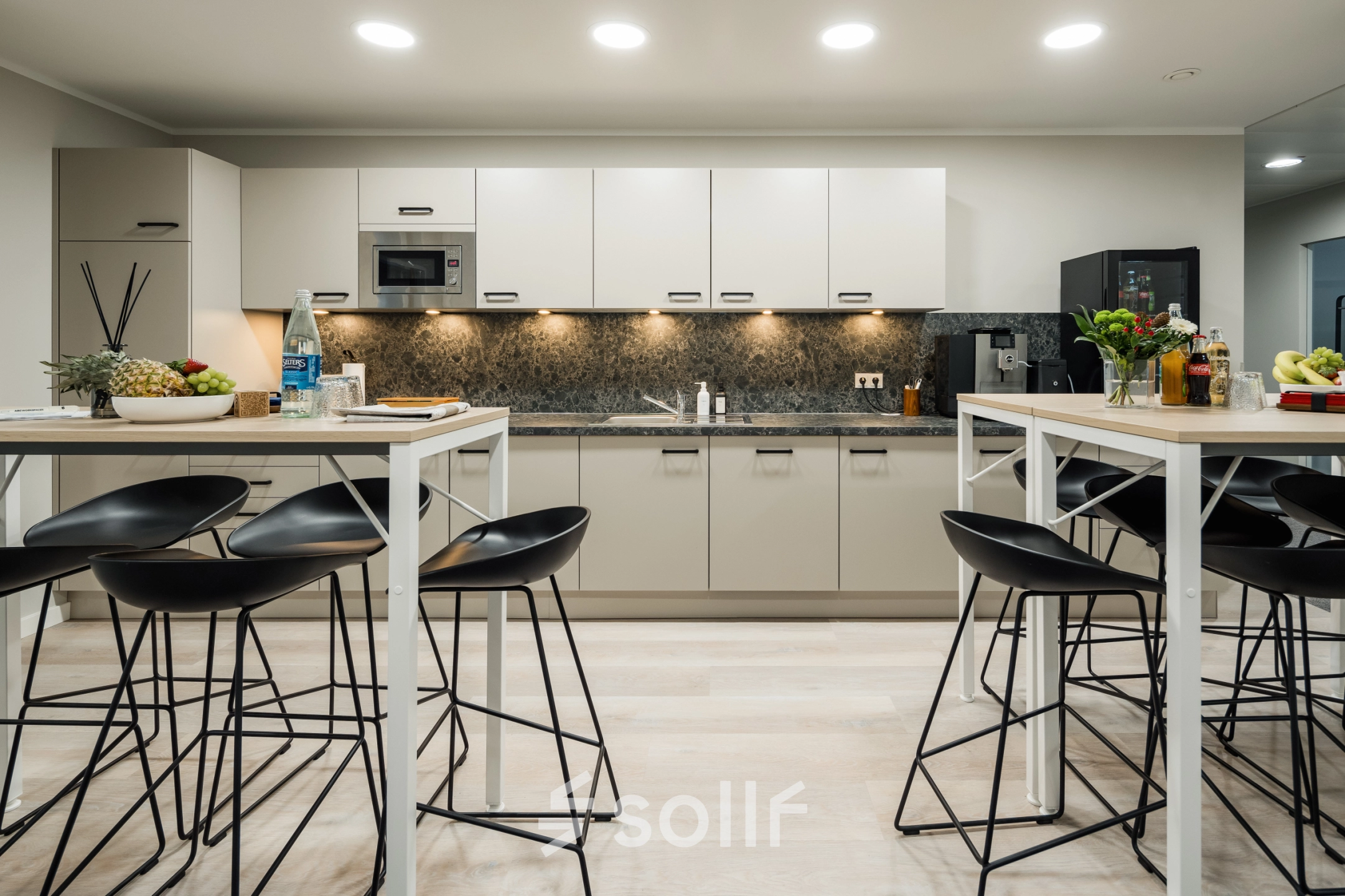 Modern pantry at Mainzer Landstraße 69, Frankfurt Central Station, featuring sleek countertops, high stools, and a well-equipped kitchenette, ideal for office space rental needs.