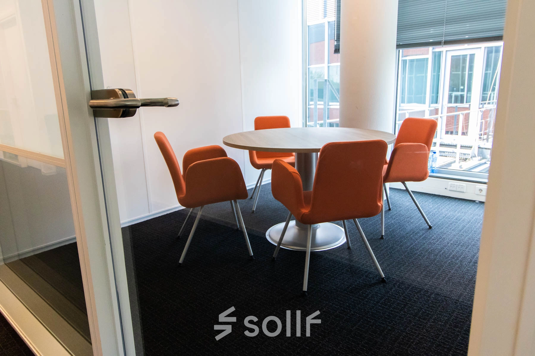 Furnished interior office space at Kampenringweg 45, Gouda, featuring a round table with four orange chairs, ideal for rent office space needs.