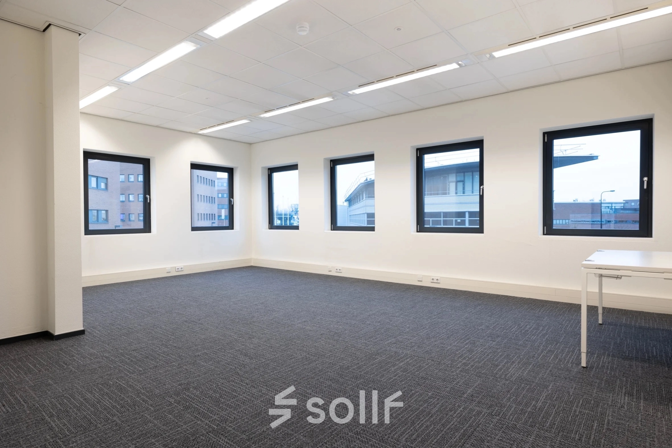 Bright office space at Zuidelijk Halfrond 1 in Gouda, available for rent with several large windows and modern carpeting.