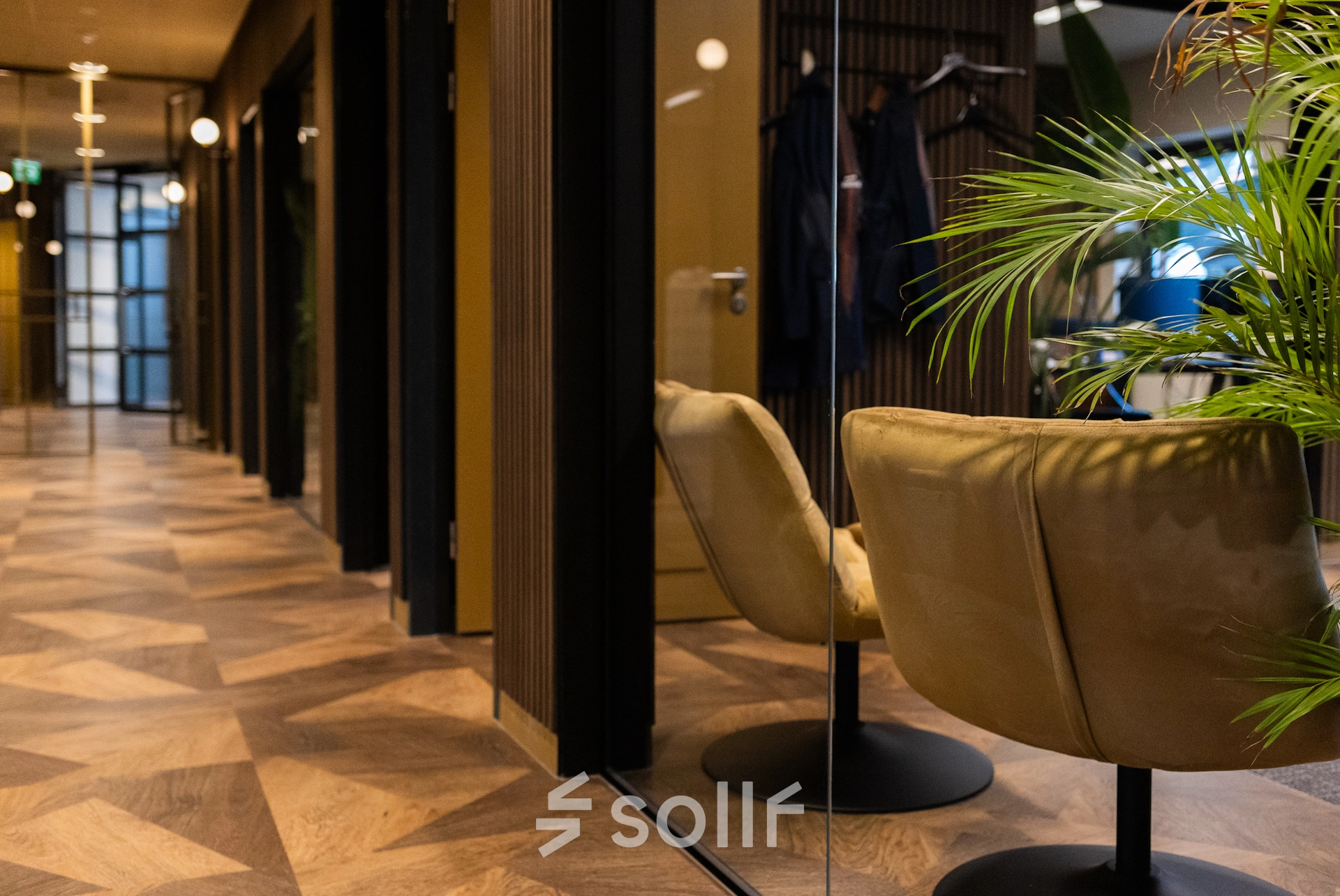 Modern office space to rent at Zuidelijk Halfrond 1, Gouda, showing a hallway with stylish chairs and potted plants, ideal for office space rental.