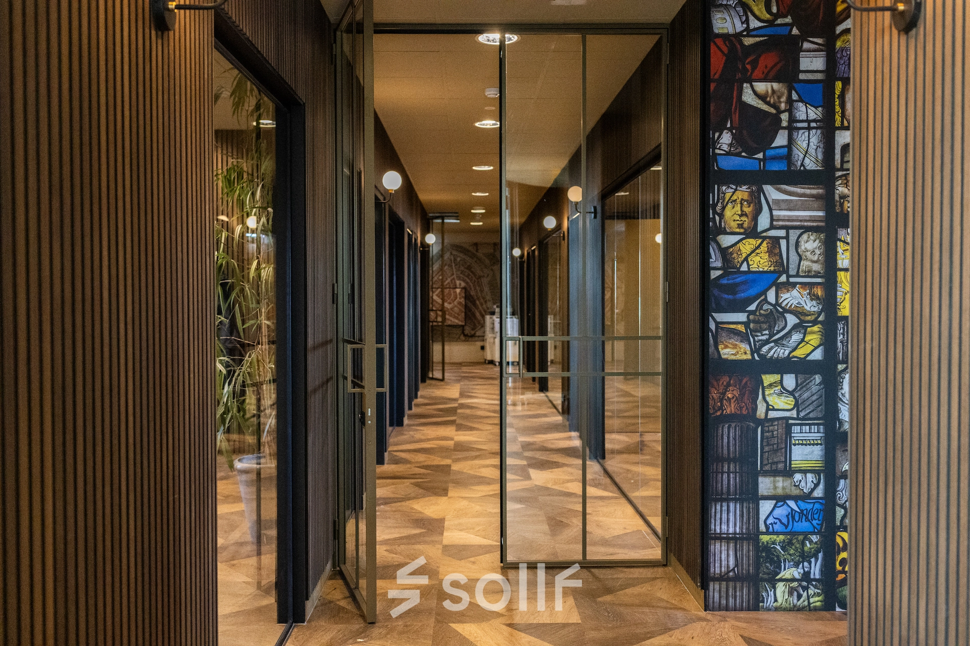 Stylish hallway in an office to rent at Zuidelijk Halfrond 1, Gouda, featuring glass doors and decorative wall art.