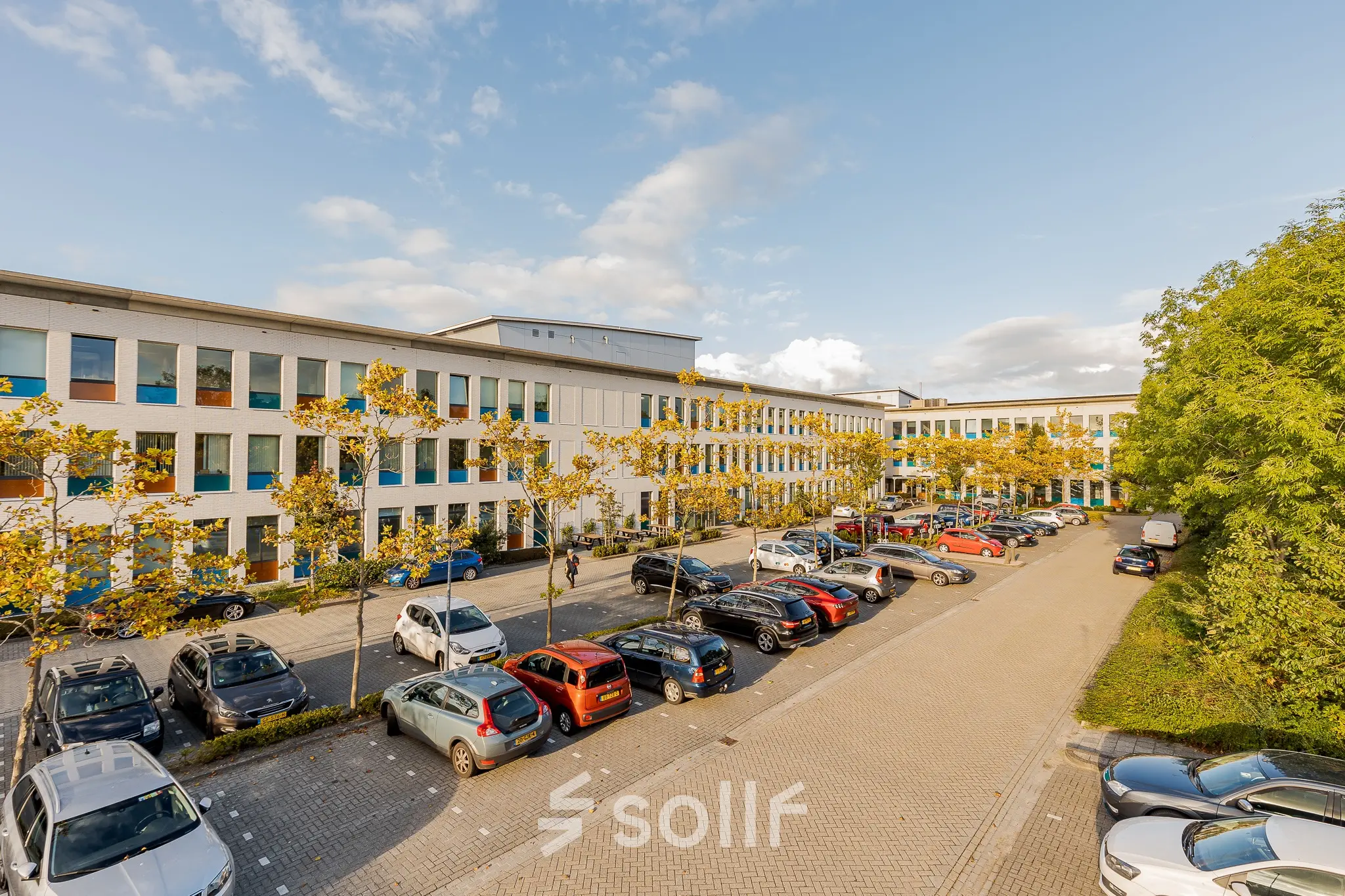 Exterior view of the office at Zernikepark 12, Groningen, featuring a parking area with multiple cars.