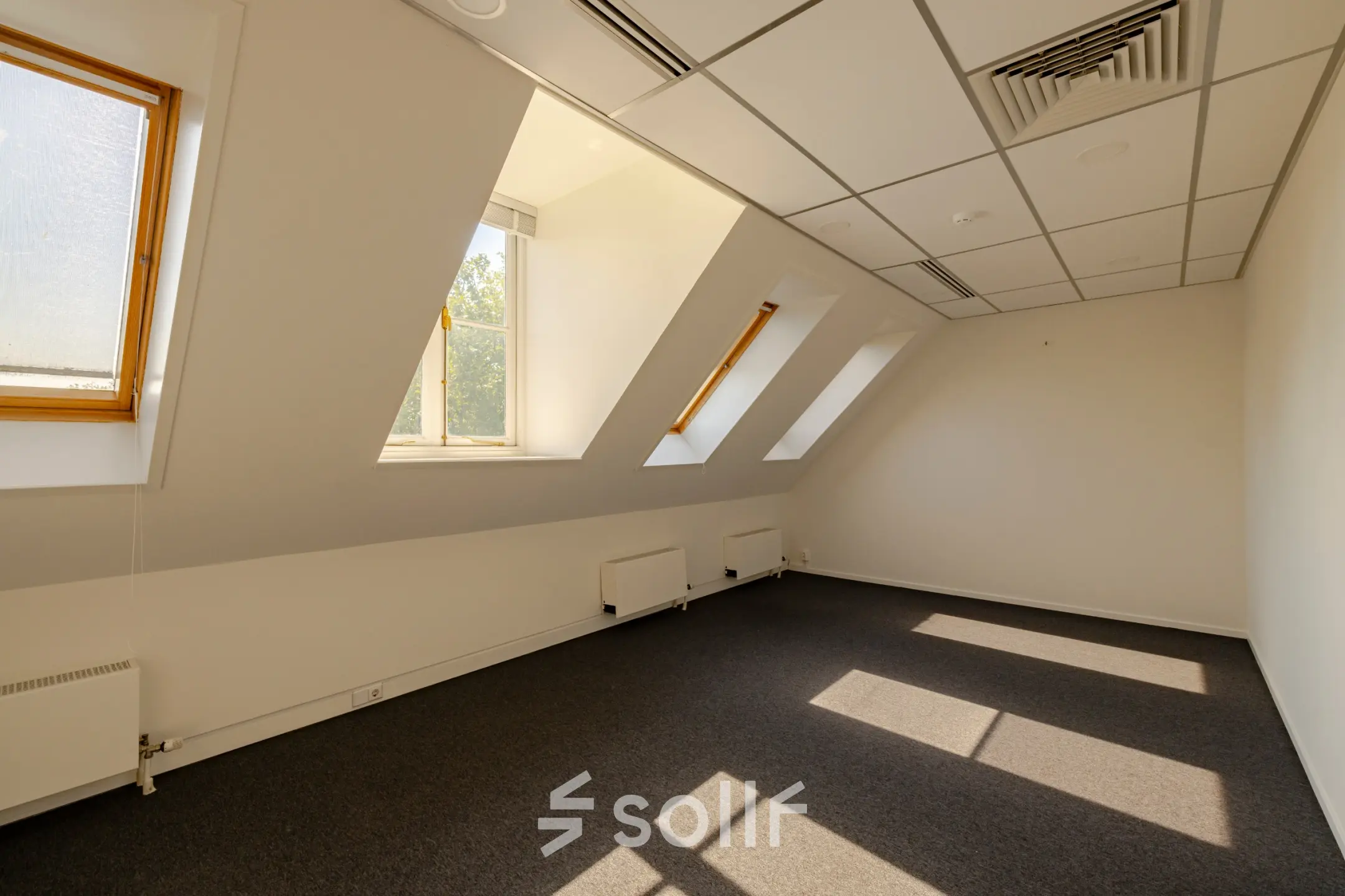 Bright office space rental at Kennemerplein 20, Haarlem Centraal Station, featuring slanted windows and ample natural light, available for rent.