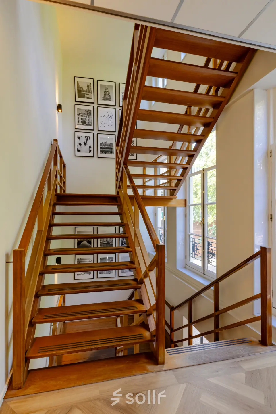 Wooden staircase with wall-mounted pictures and a window at Kennemerplein 20, ideal for office space rental at Haarlem Centraal Station.