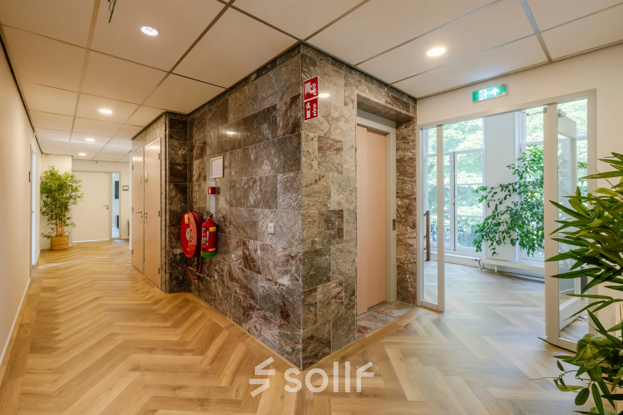 Hallway with wooden flooring and a marble wall near elevator at Kennemerplein 20, Haarlem Centraal Station, ideal for office space rental.