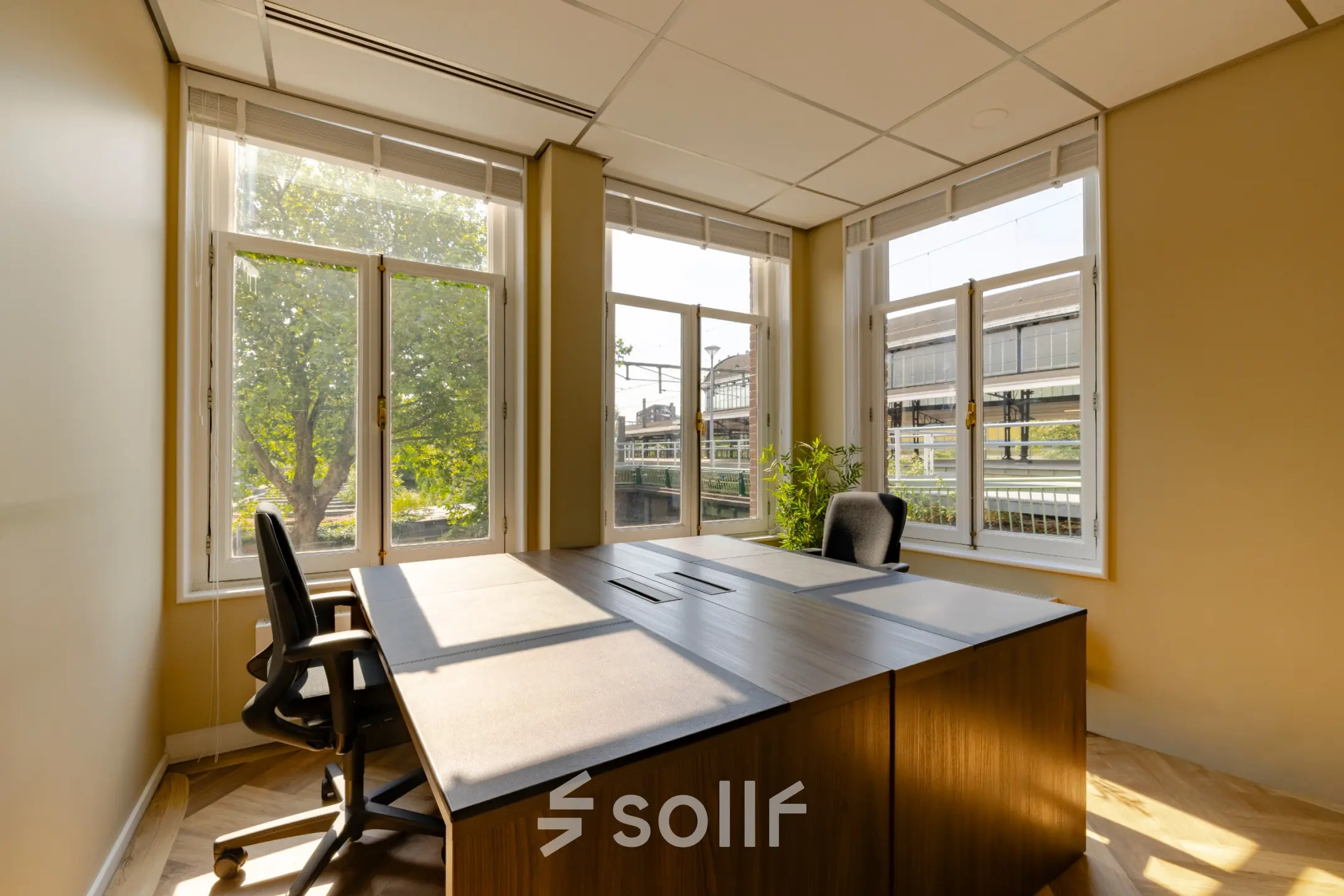 Bright furnished office space for rent at Haarlem Centraal Station, featuring large windows and modern furniture, ideal for focused work.