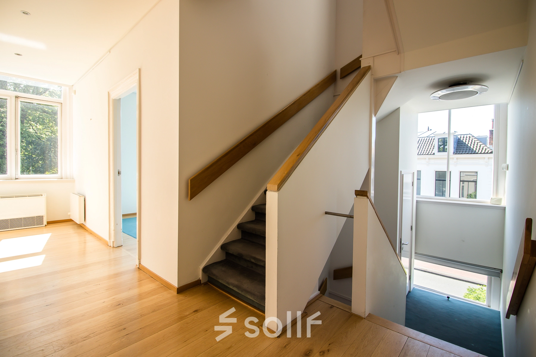 Bright interior view of an unfurnished office space available for rent at Prinsen Bolwerk 1, Haarlem Centraal Station, featuring wooden floors, large windows, and a staircase.
