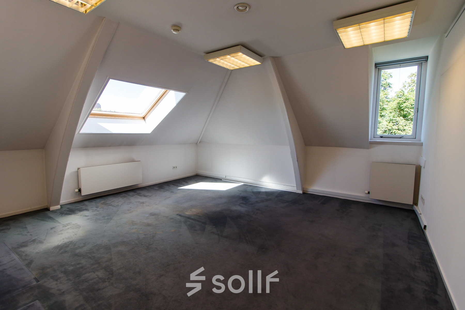 Bright, unfurnished office space available for rent at Prinsen Bolwerk 1, near Haarlem Centraal Station, featuring a large skylight and modern lighting.