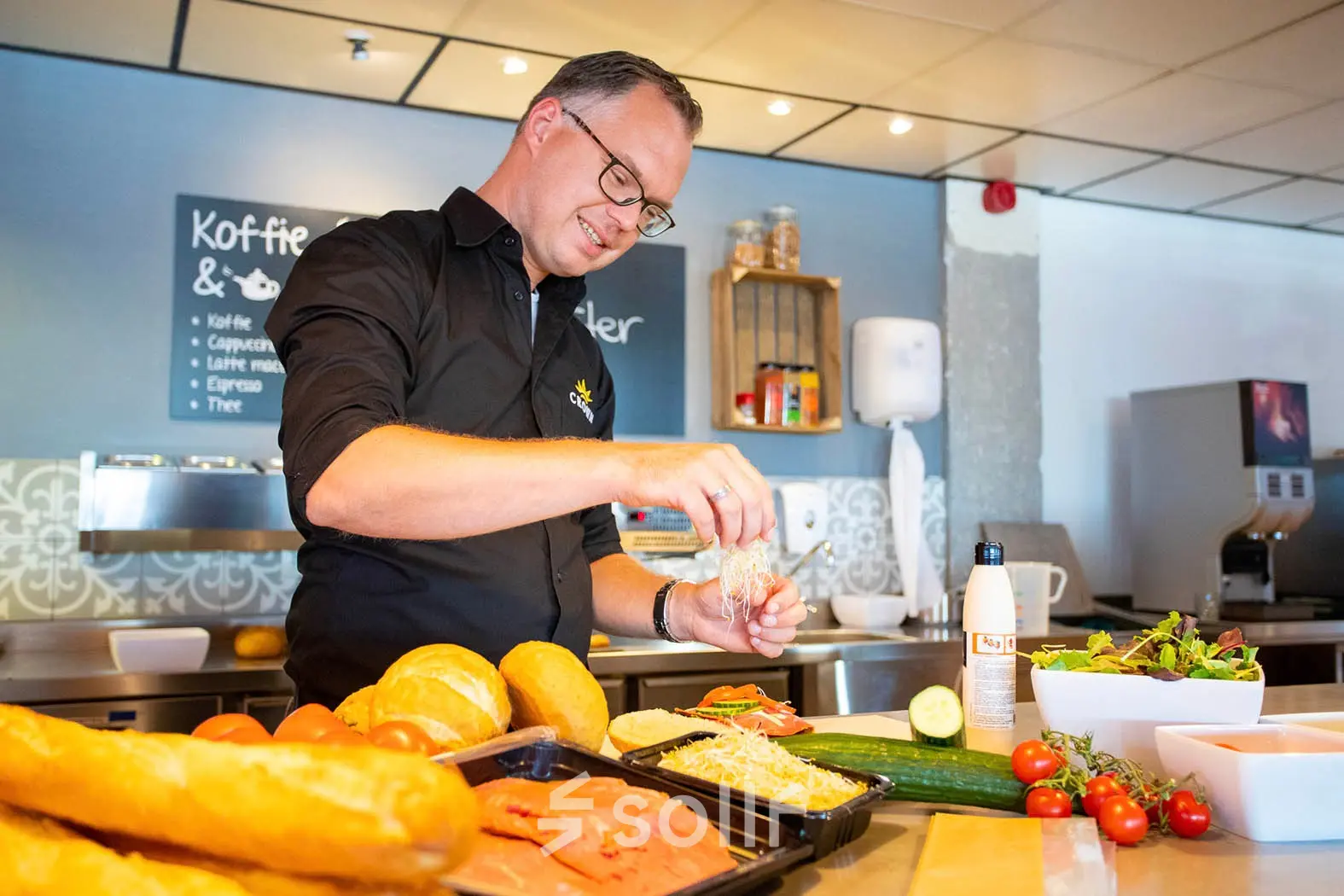 Individual preparing fresh sandwiches and salads in a modern office pantry at A. Hofmanweg 5A, Haarlem Waarderpolder. Ideal for entrepreneurs seeking office space rental with convenient amenities.