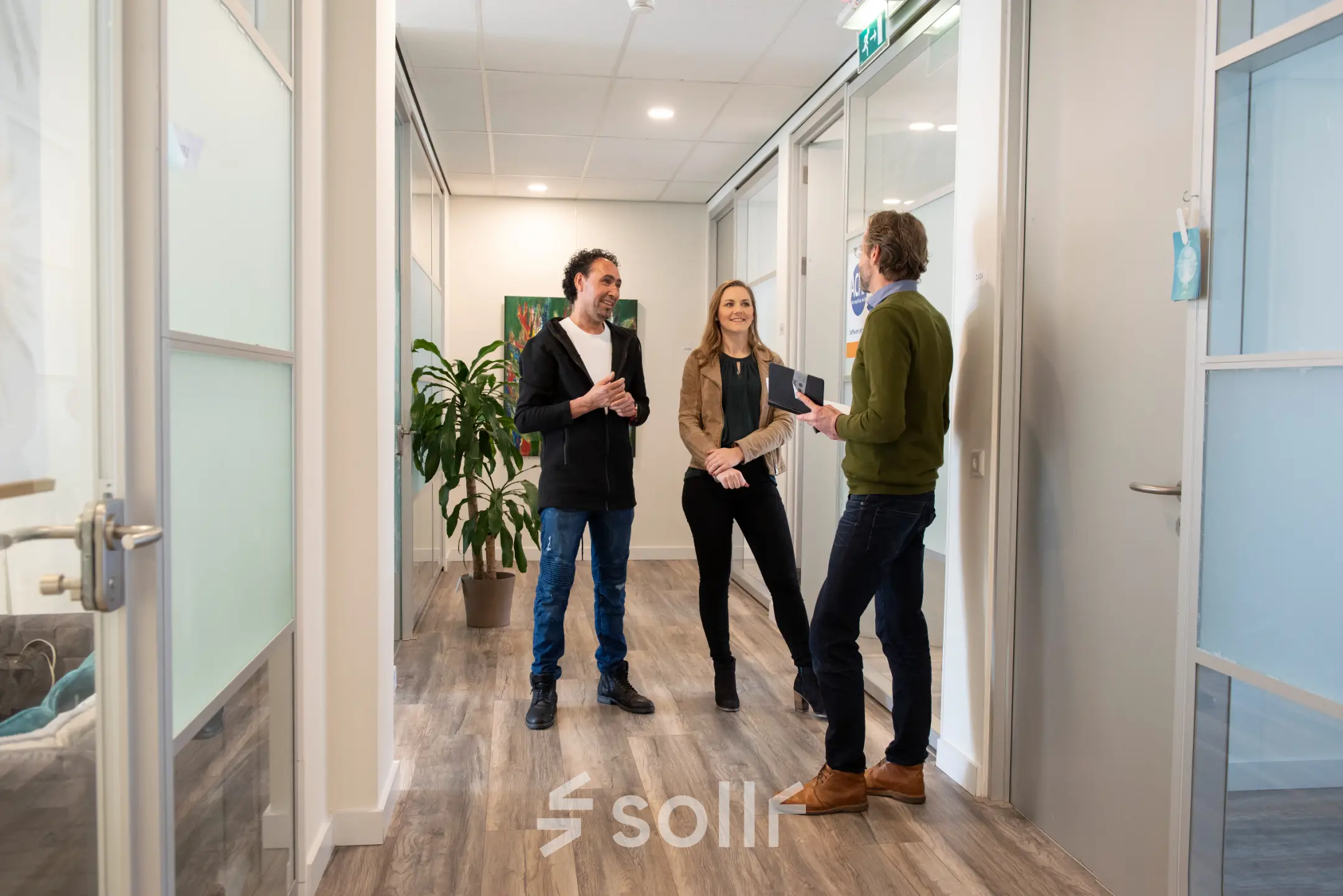 Three people engaged in a discussion in a modern office hallway at Waarderweg 19, highlighting the collaborative environment of this office space rental in Haarlem Waarderpolder.