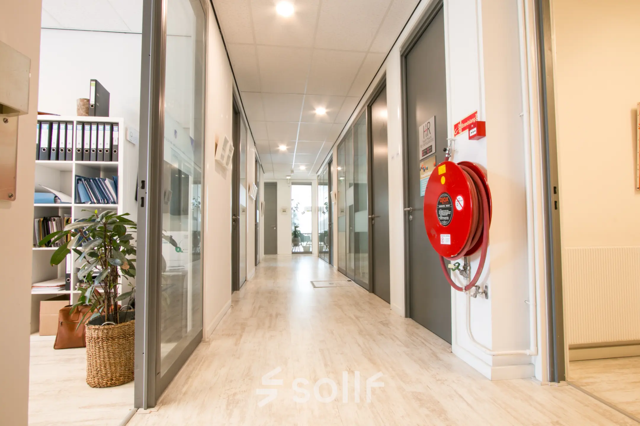 Bright hallway in Haarlem Waarderpolder's office to rent, featuring glass doors and a wooden floor.