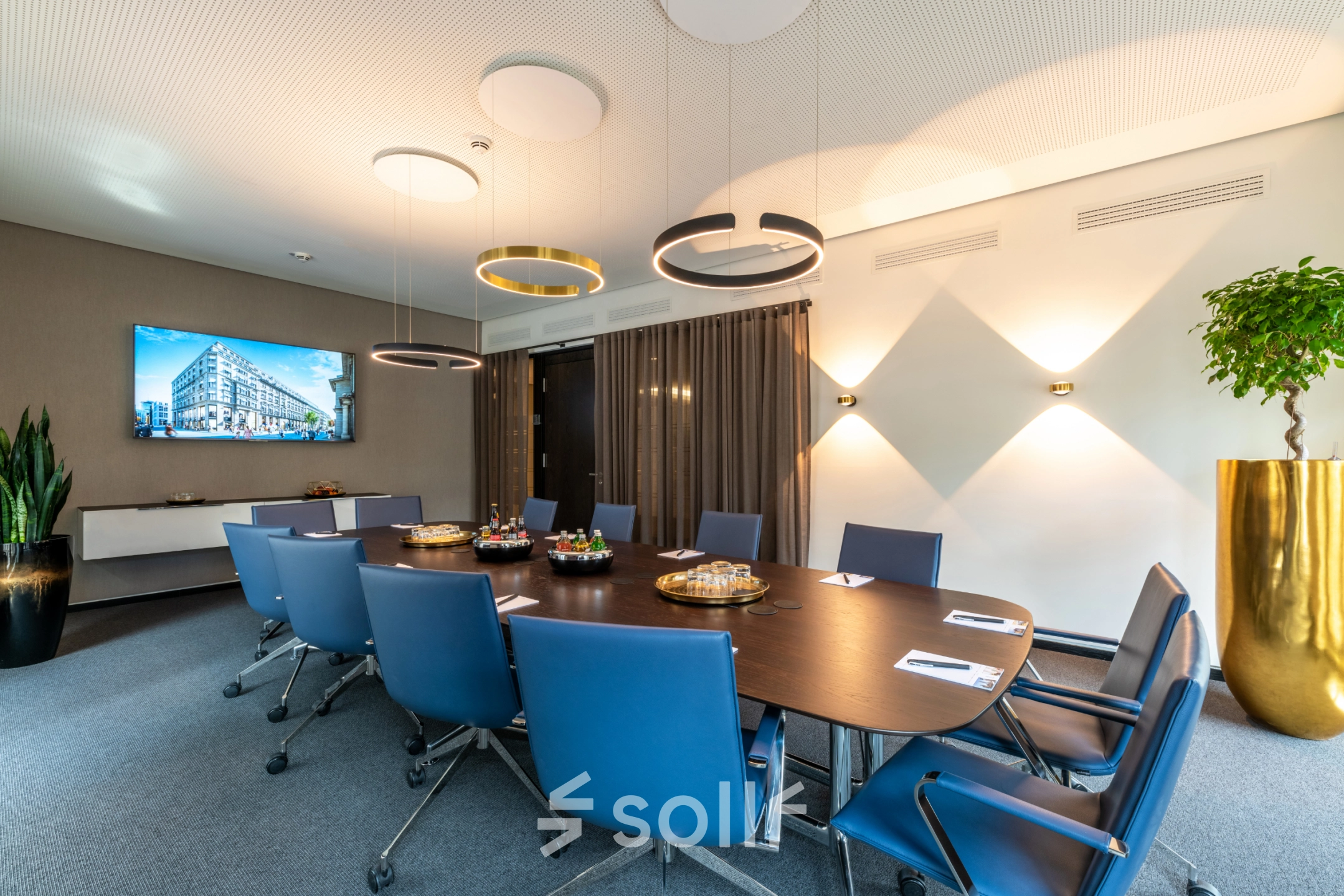 Modern conference room with a large table, blue chairs, and a TV on the wall, suitable for office space rental in Hamburg Old Town.