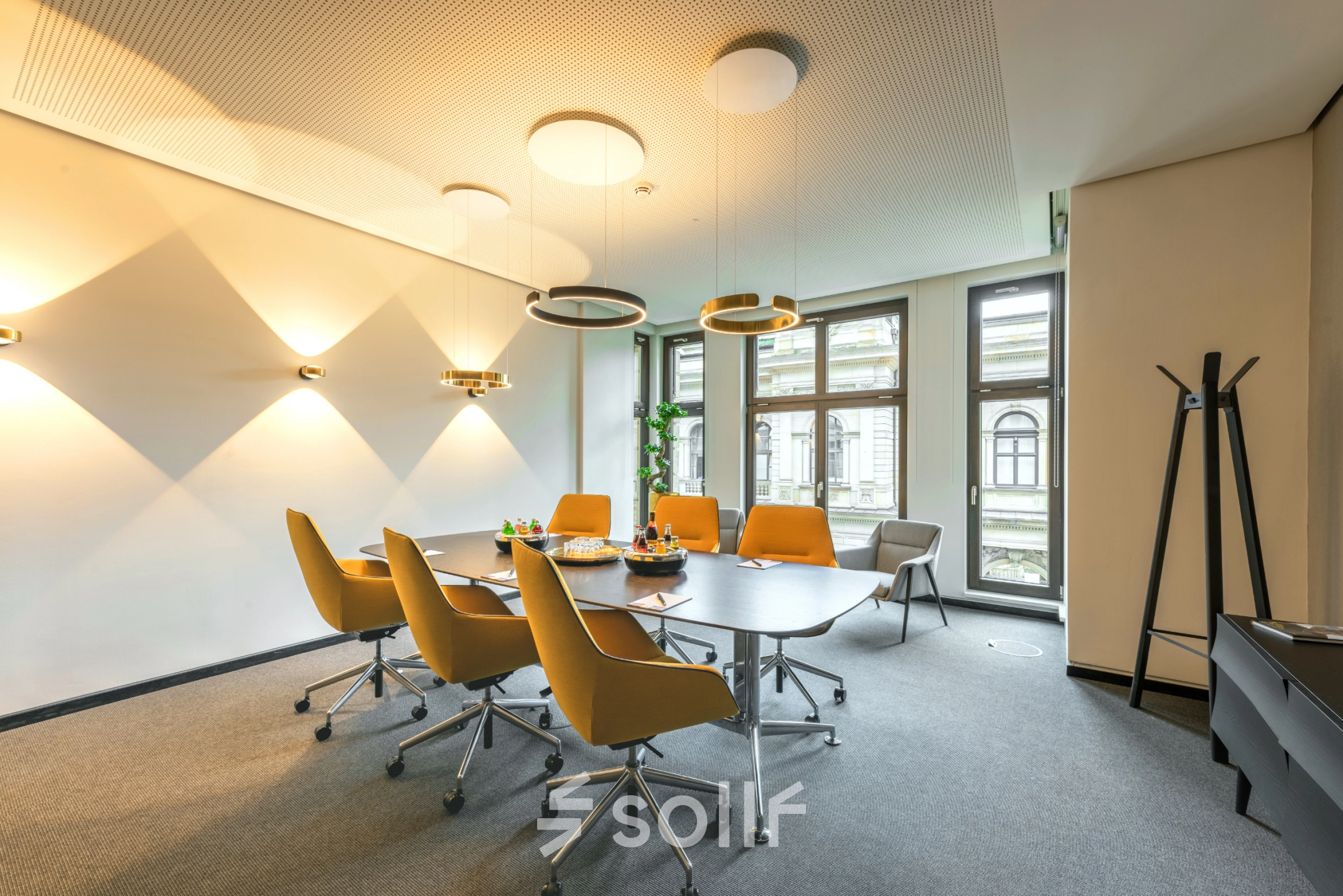 Modern office space for rent at Alter Wall 32, Hamburg Old Town, featuring a furnished conference room with a large table and chairs under stylish lighting.