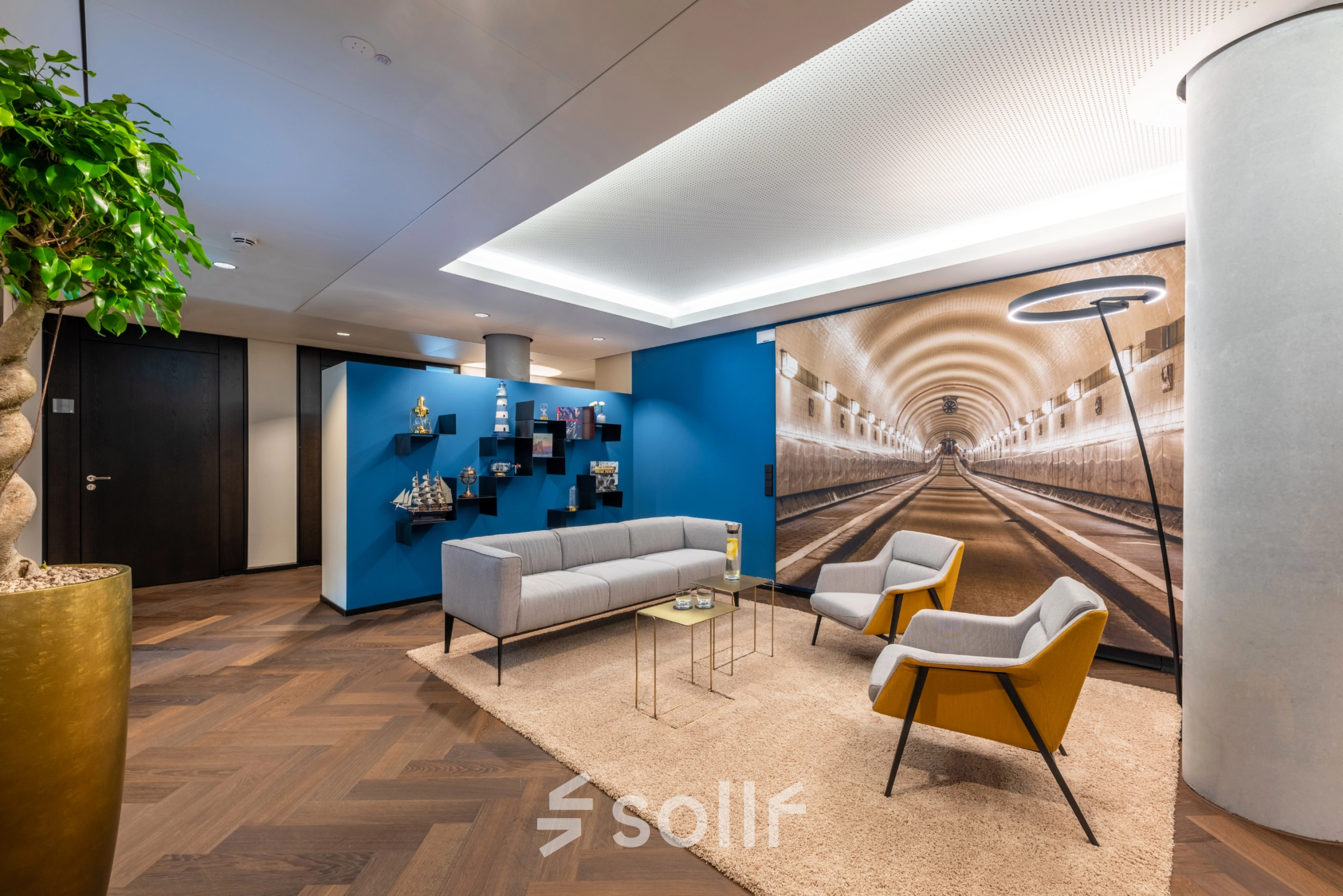 Stylish office lounge with modern furnishings, vibrant decor, and a tunnel mural, ideal for office space rental in Hamburg Old Town.
