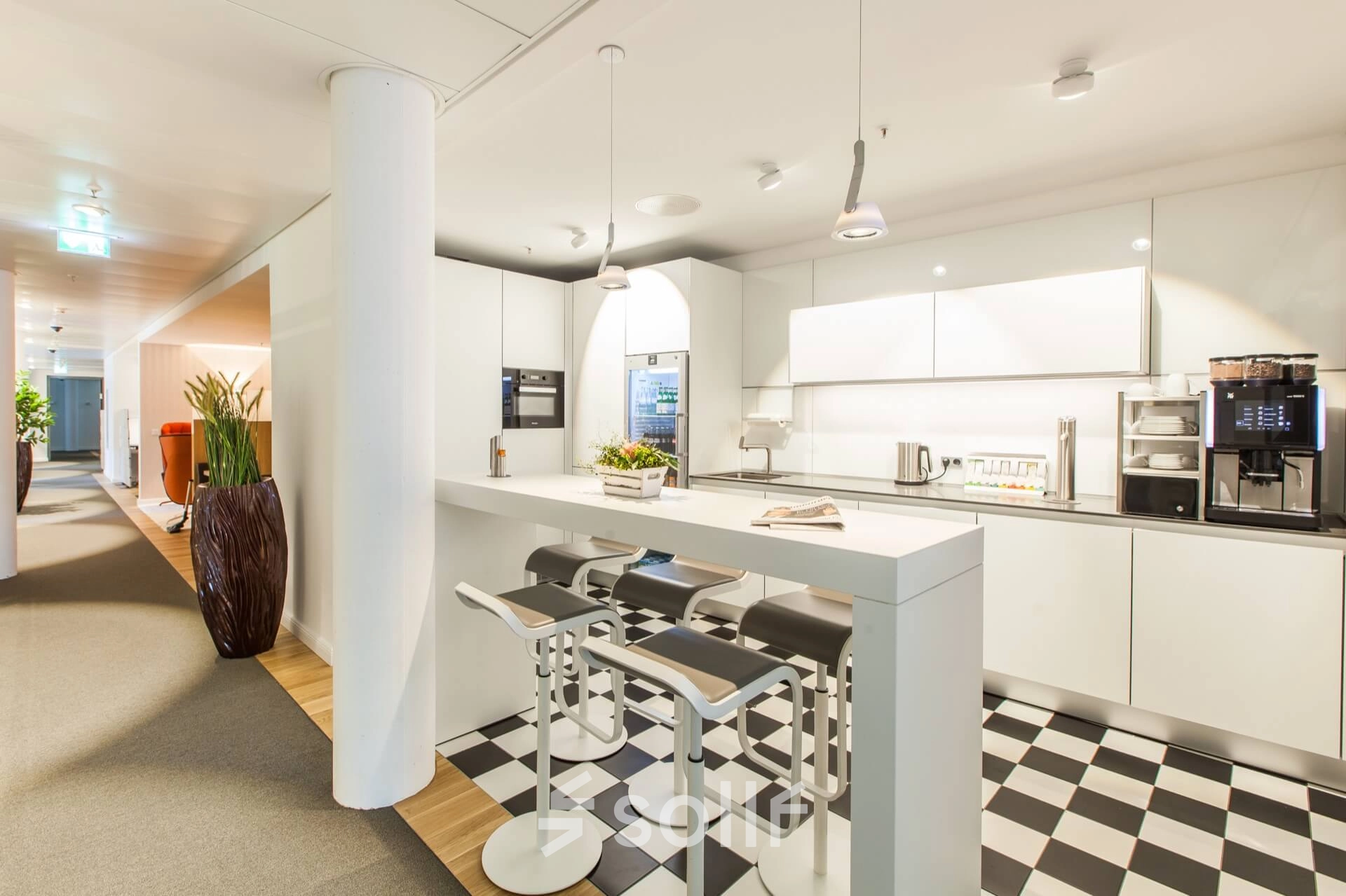 Modern office kitchen at Ballindamm 39, Hamburg Old Town, featuring a sleek white kitchenette with bar seating, ideal for breaks in an office space rental.
