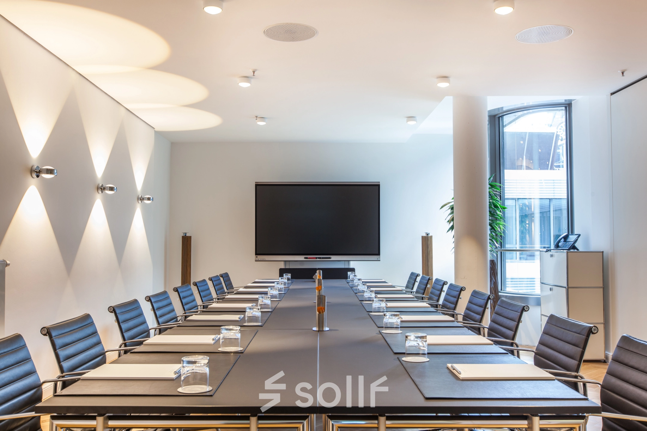 Spacious conference room at Ballindamm 39, Hamburg Old Town, featuring a long table, chairs, and presentation screen, ideal for office space rental.