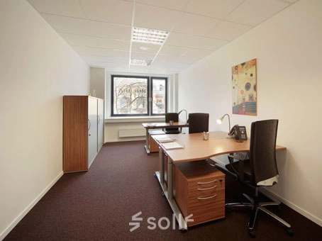 A bright office space with two desks, chairs, and a cabinet, located at Bahnhofstraße 8 in Hannover Mitte. Ideal for office space rental with natural light from large windows.