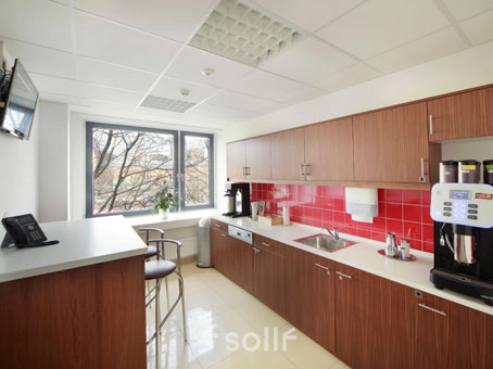 Bright, furnished office space rental in Hannover Mitte with a modern kitchenette, featuring sleek cabinetry and coffee machine, perfect for a break or casual meeting.