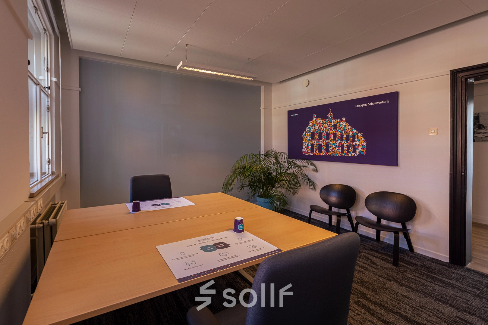 Modern office space at Ceintuurbaan 2, Harderwijk features sleek wooden tables, black chairs, and vibrant wall art, perfect for dynamic meetings. Ideal for office space rental seekers.