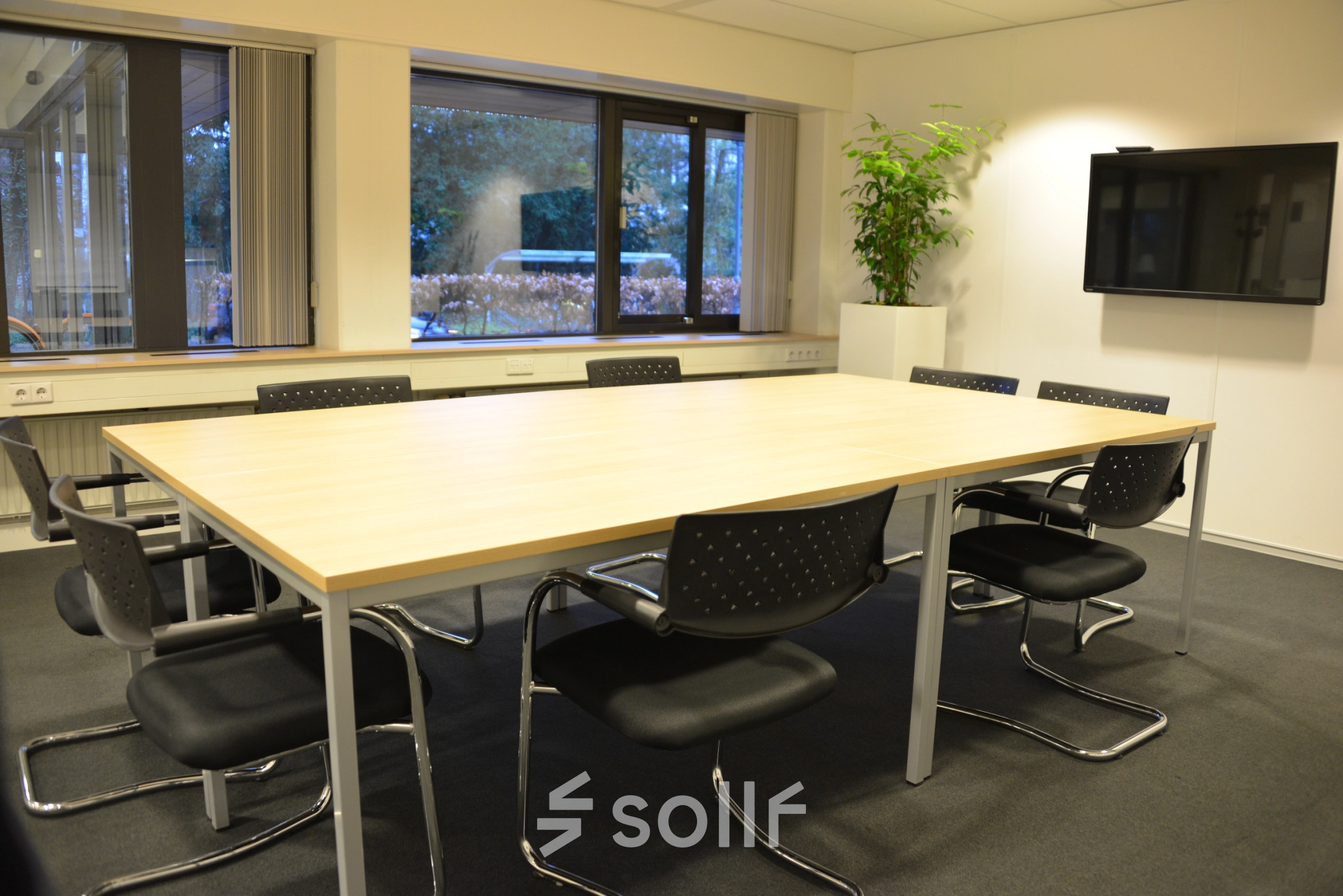 Furnished office space at Herenweg 115, Heemstede, featuring a large table and chairs suitable for meetings or collaborative work. Ideal for office space rental.