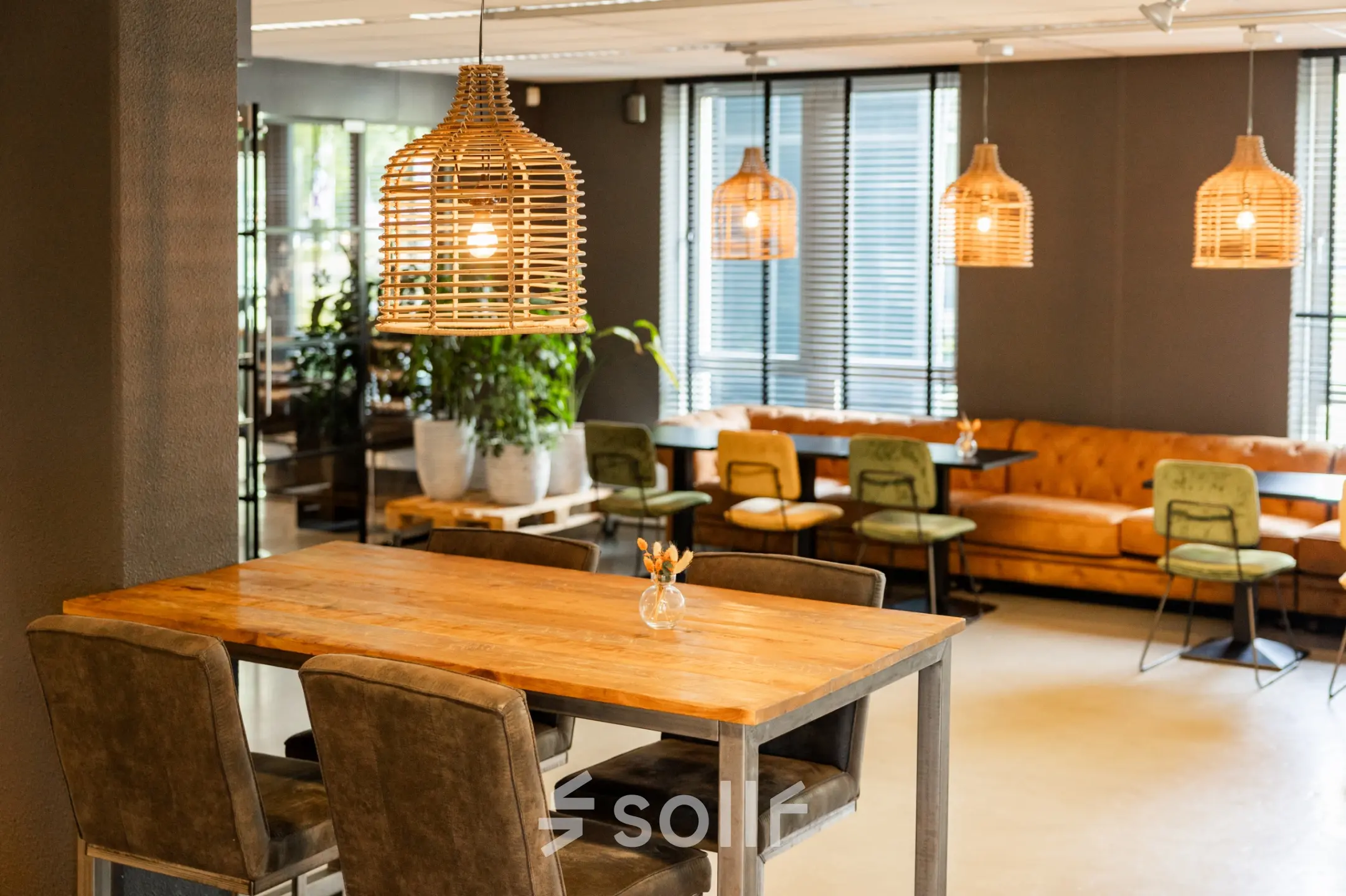 Stylish and furnished office space for rent at Demmersweg 3, Hengelo, featuring modern seating, ambient lighting, and wooden tables in a welcoming lounge area.