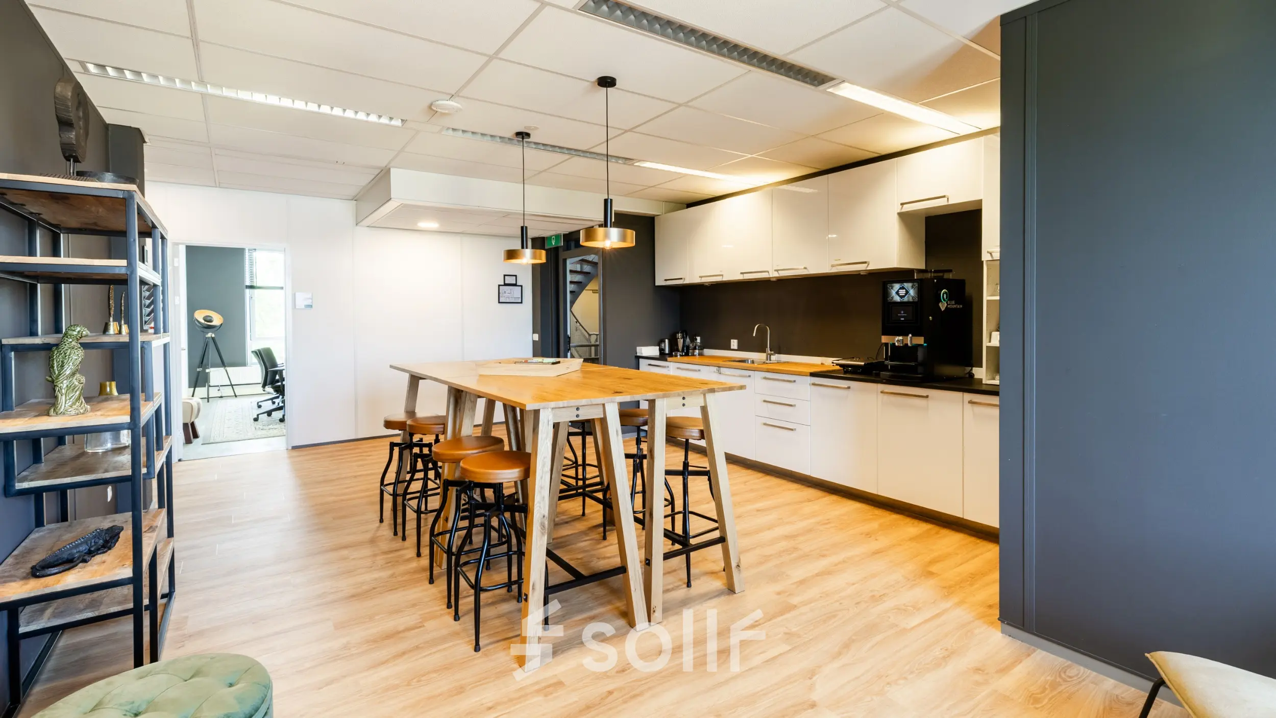 Modern office kitchen area with wooden table, bar stools, and equipped kitchen facilities at Demmersweg 3 in Hengelo, ideal for office space rental.