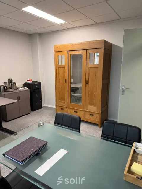 Furnished office space at Hamerstraat 10, Hengelo, featuring a glass table and wooden cabinet, available for office space rental.
