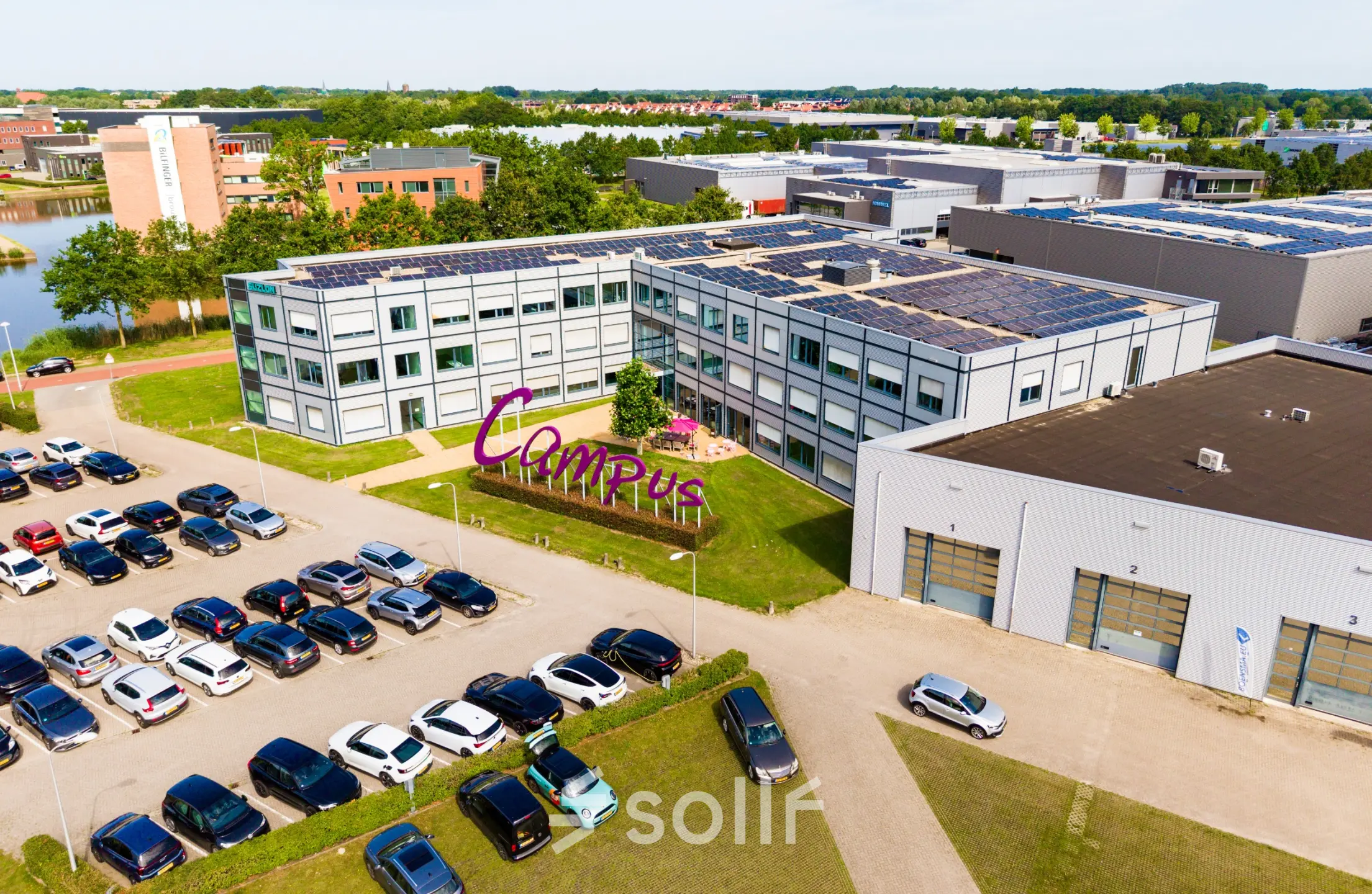 Exterior view of office space available for rent at Jan Tinbergenstraat 202, Hengelo, featuring solar panels on the roof and a large parking area.