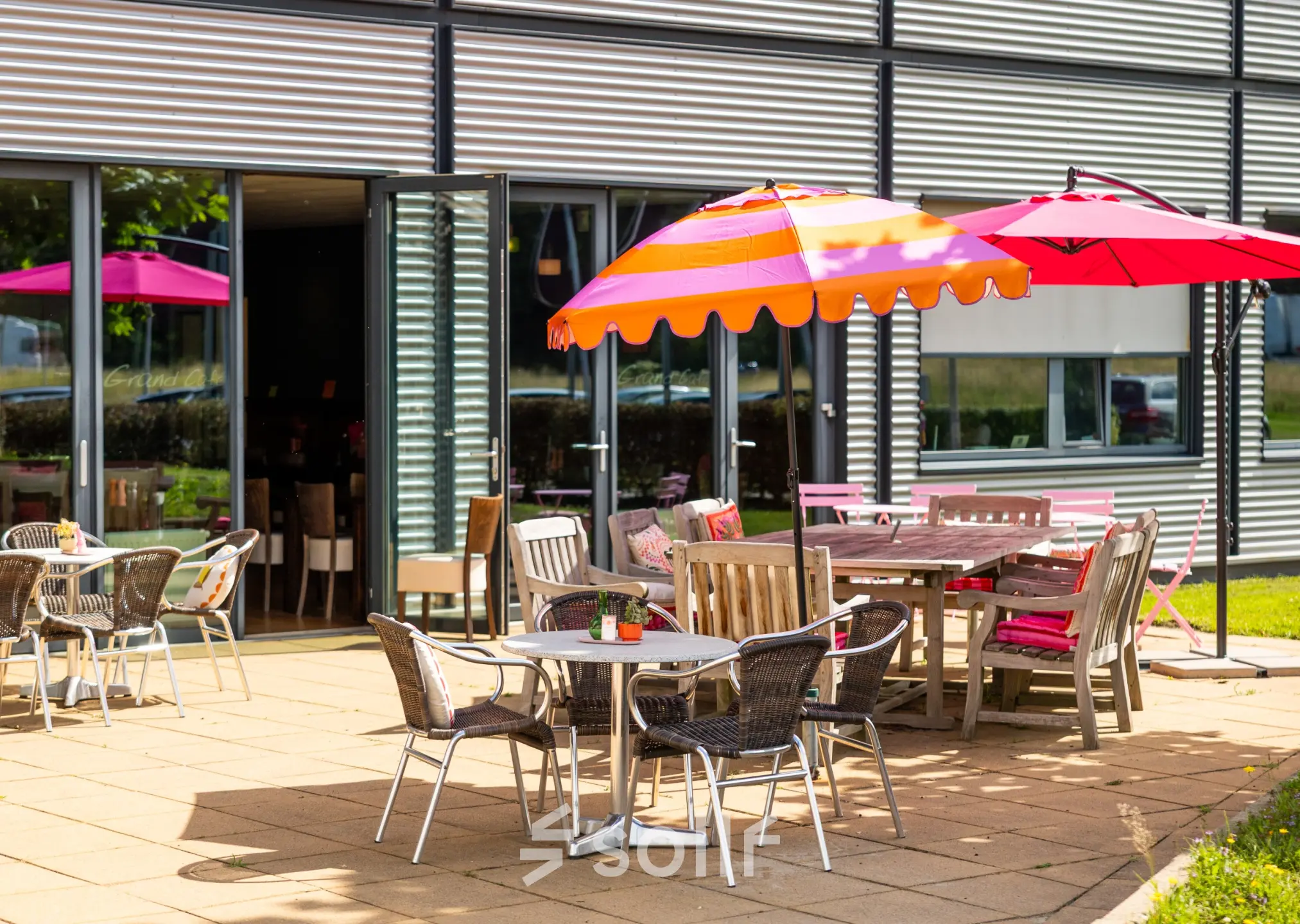 Outdoor office space rental at Jan Tinbergenstraat 202, Hengelo, featuring colorful patio furniture and umbrellas for informal meetings or breaks.