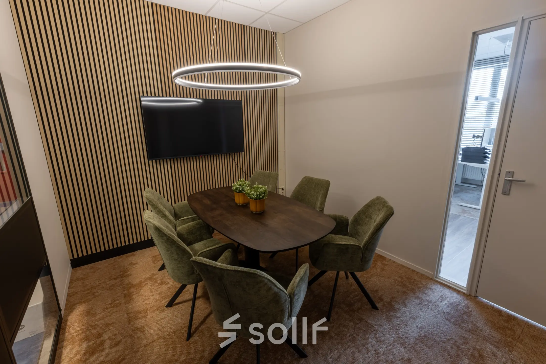 Stylish office space with a wooden meeting table and green chairs at Lansinkesweg 4, ideal for office space rental in Hengelo.