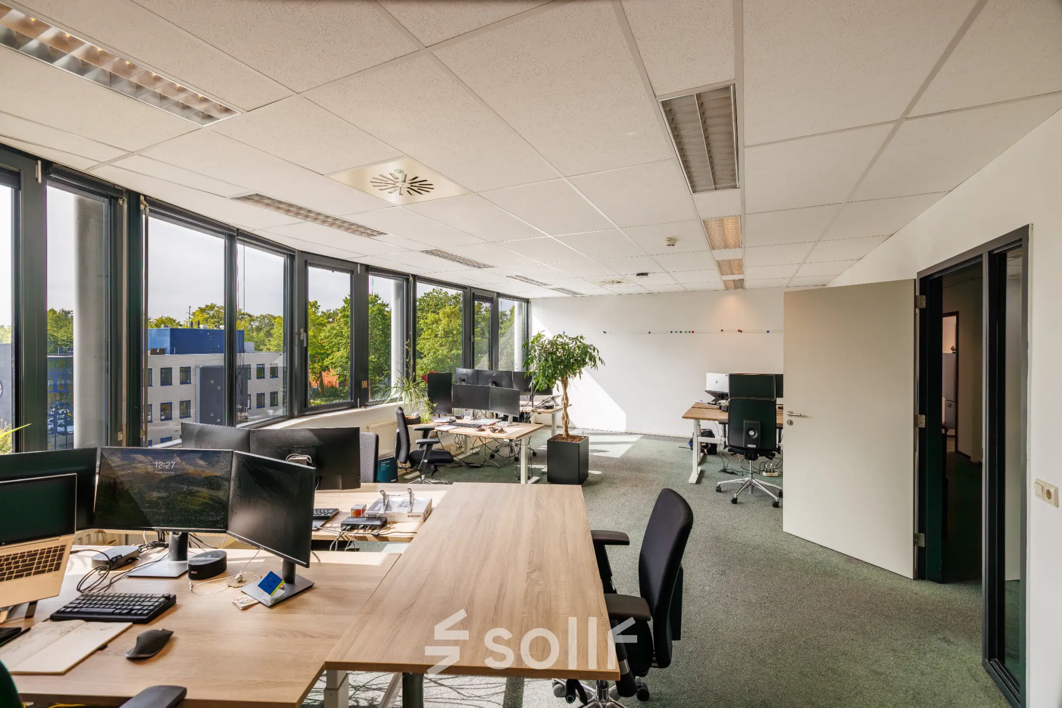 Bright and contemporary office space with workstations, large windows, and modern furnishings at Welbergweg 60, Hengelo. Ideal for businesses seeking office space rental with natural light and functional design.