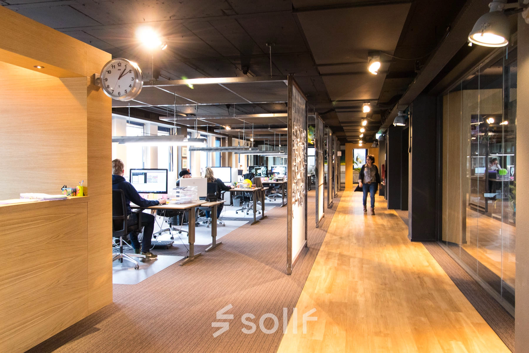 A modern office space with people working at desks, located at Franciscusweg 219, Hilversum. Ideal for office space rental, it offers a productive work environment.
