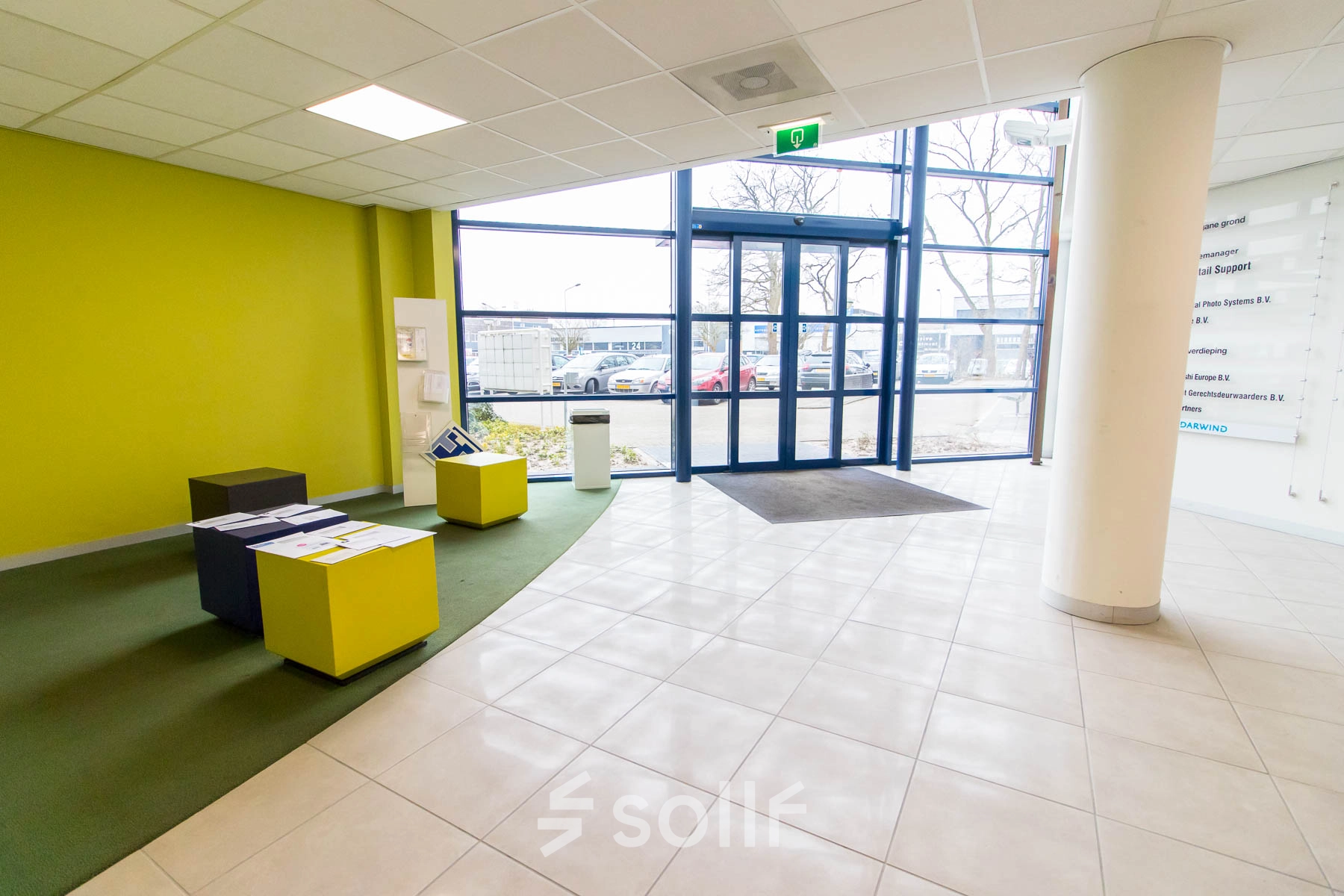 Bright entrance area at Franciscusweg 219 in Hilversum, ideal for office space rental, featuring colorful seating and large windows for natural light.
