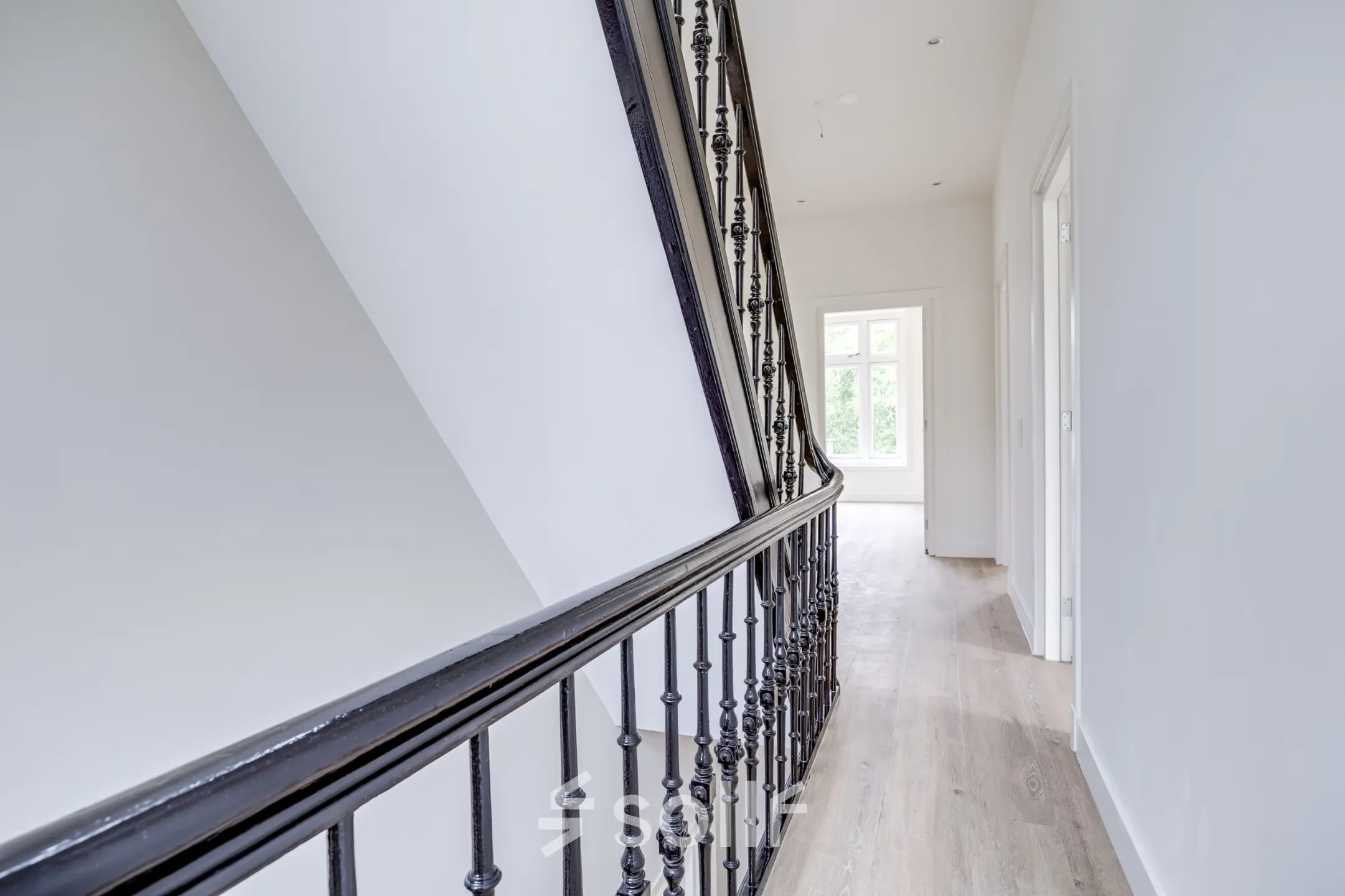 Bright hallway with wooden flooring and elegant railing at office space rental in Hilversum.